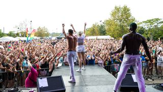 People stand on a stage waving in front of a very large crowd 