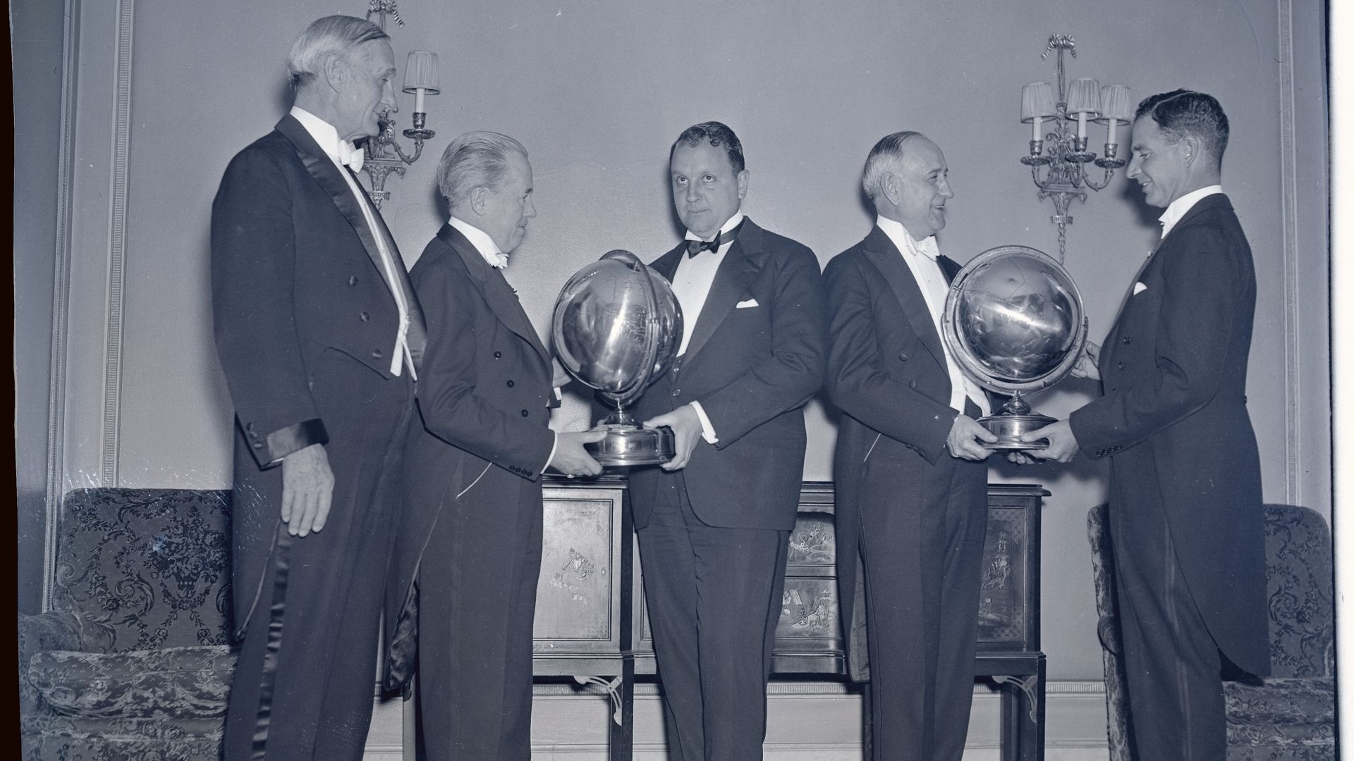 Several men and two globes, all black and white