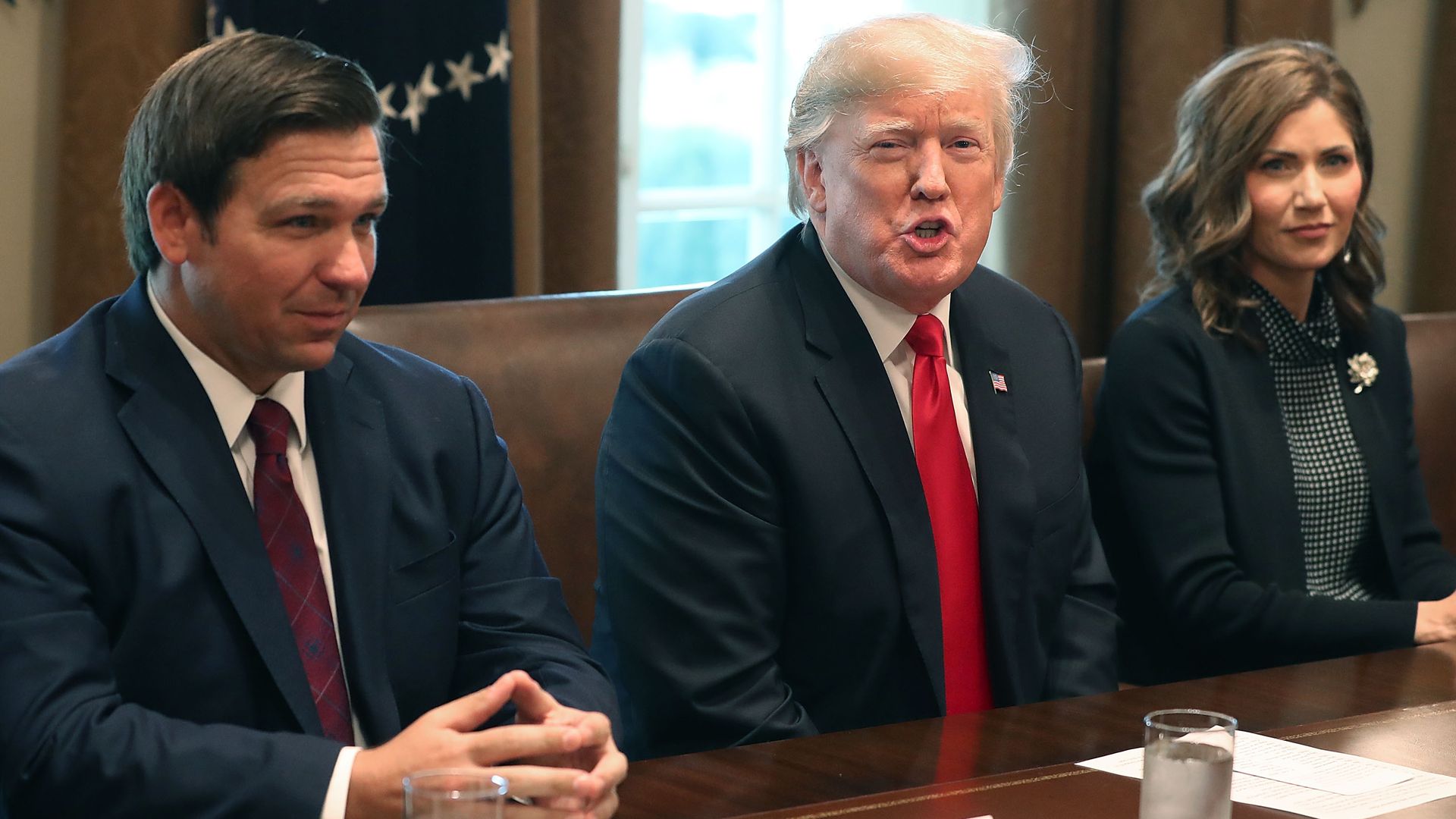 Ron DeSantis (R) sits next to U.S. President Donald Trump and Governor of South Dakota-elect Kristi Noem