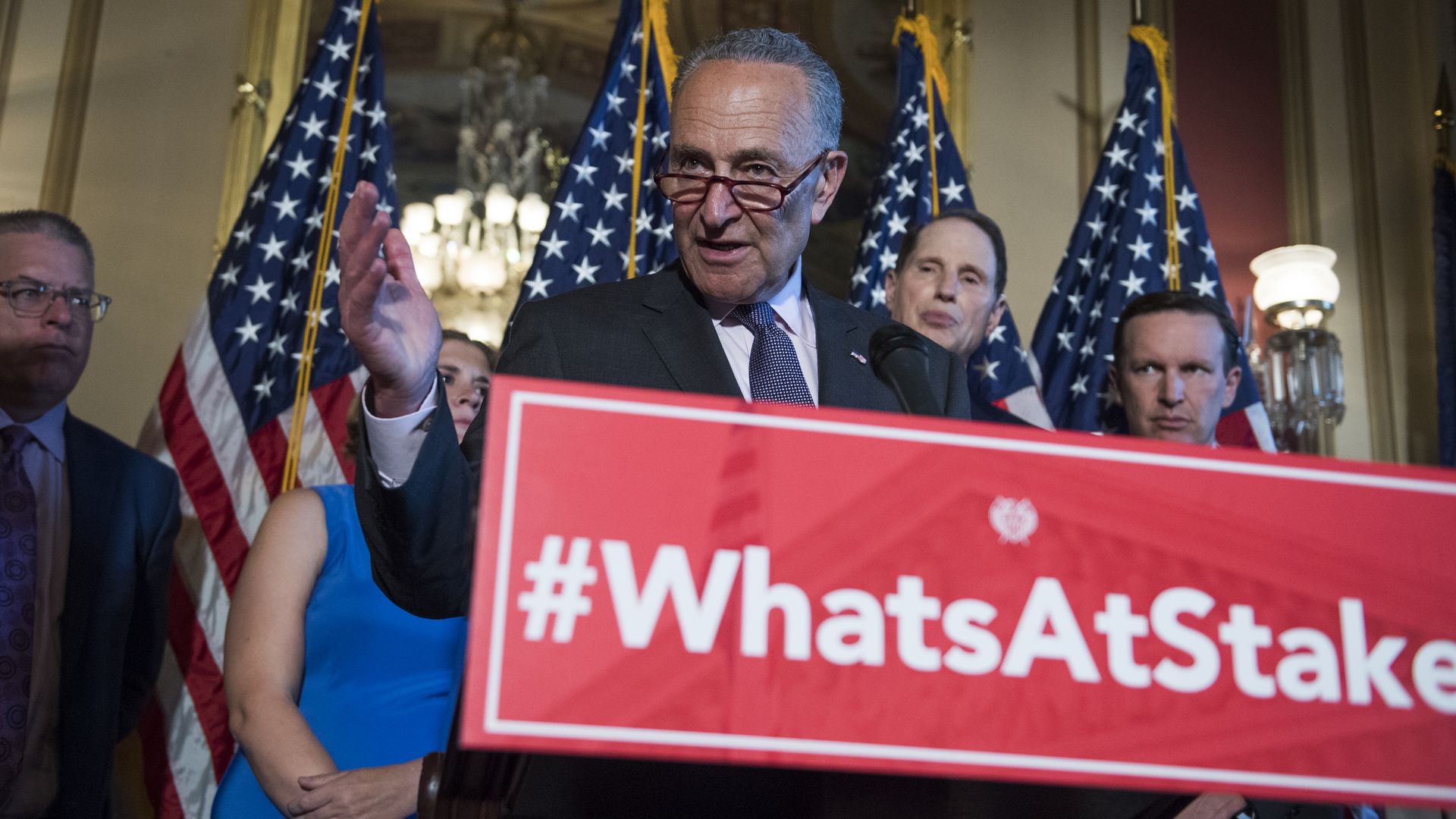 Senate Democrats hold a press conference; the podium reads "What's at stake"
