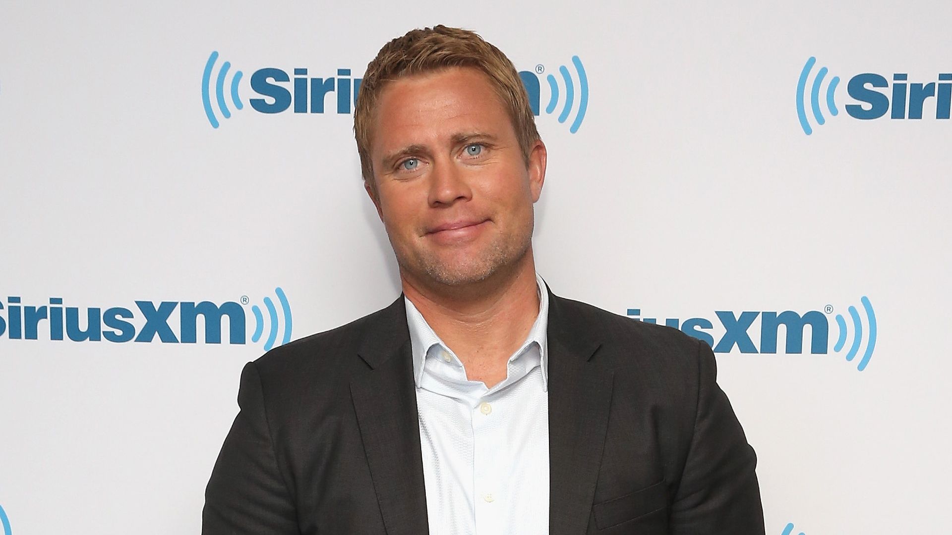 Tim Ballard, founder and ex-CEO of Operation Underground Railroad poses in front of a screen with a SiriusXM logo. 