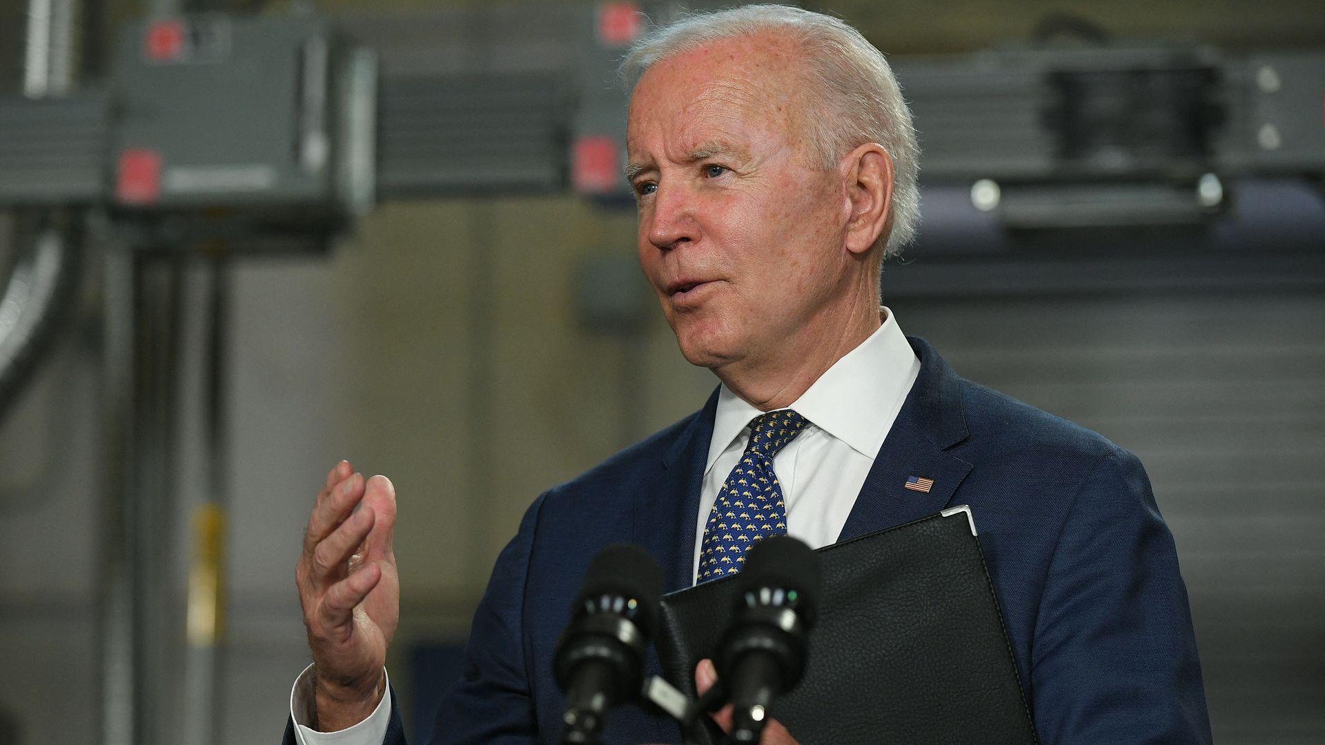 Biden pictured here wearing a suit and standing in front of a podium 