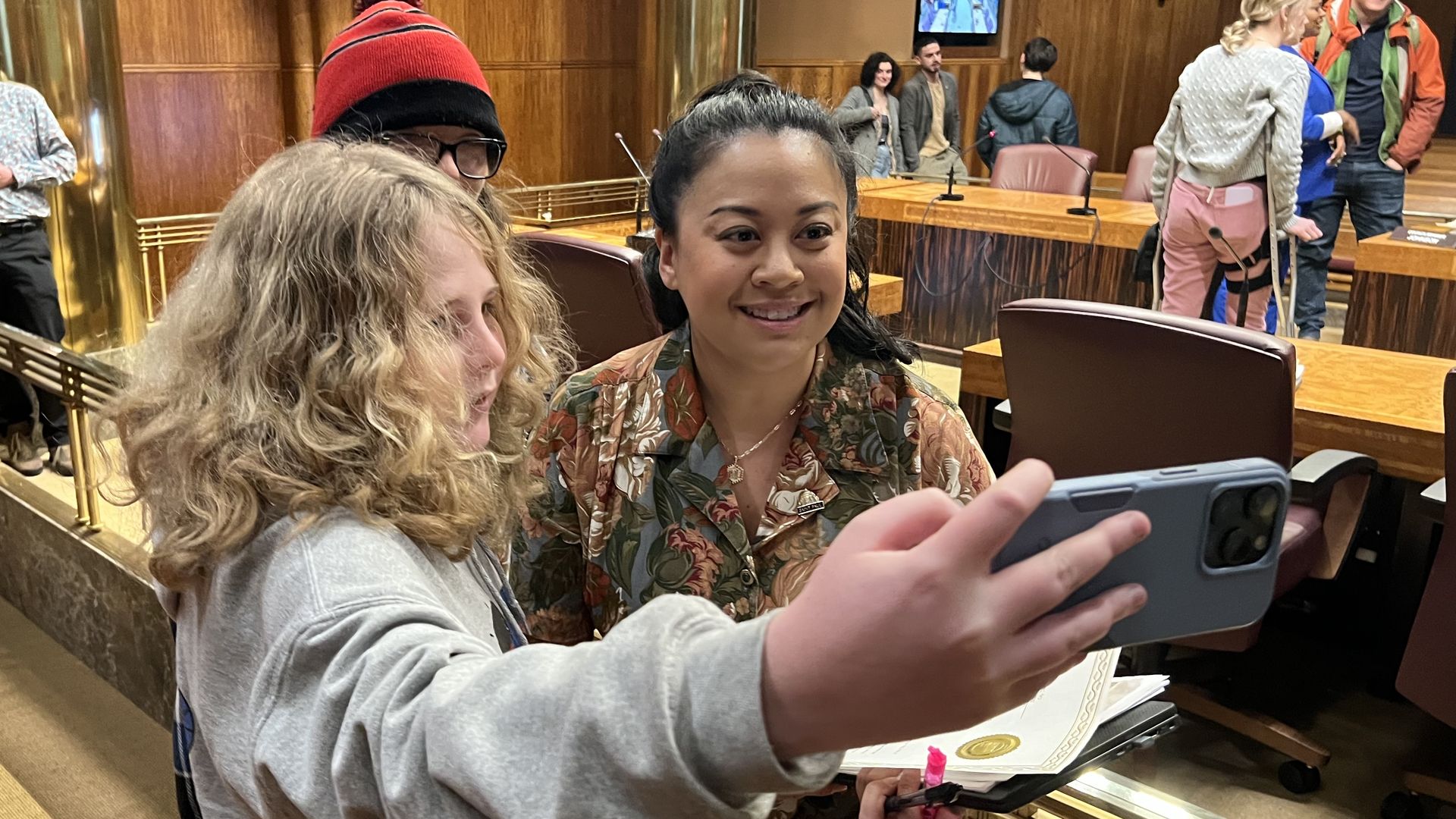 A woman poses for a selfie photograph with a young person.