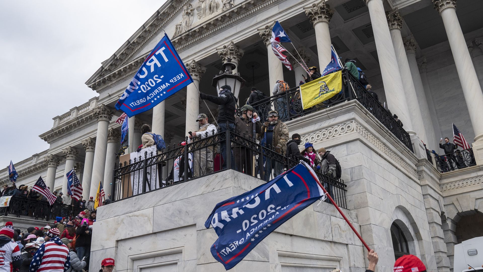People wave "TRUMP 2020 KEEP AMERICA GREAT!" flags outside of the U.S. Capitol.