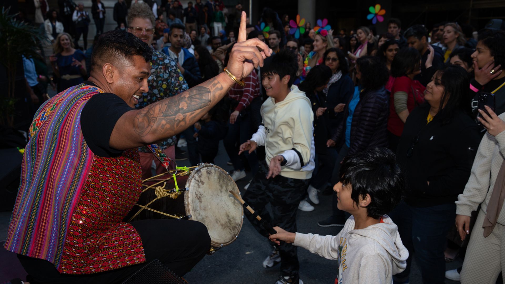 Photo of a drummer smiling at a child at the front of a dancing crowd