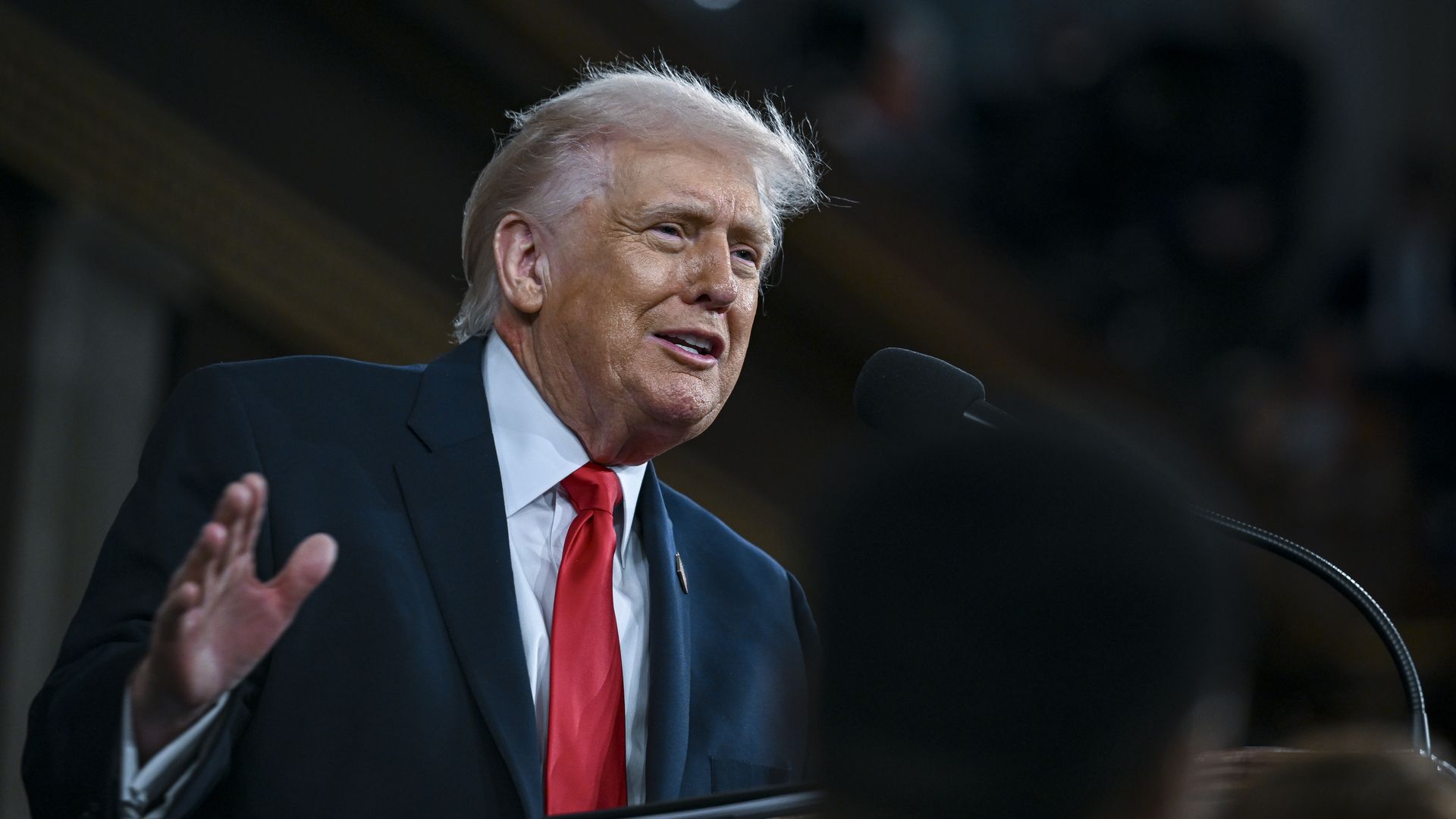 President Donald Trump speaks at a podium in the House Chamber of the U.S. Capitol during the State of the Union address as members of Congress sit behind him.