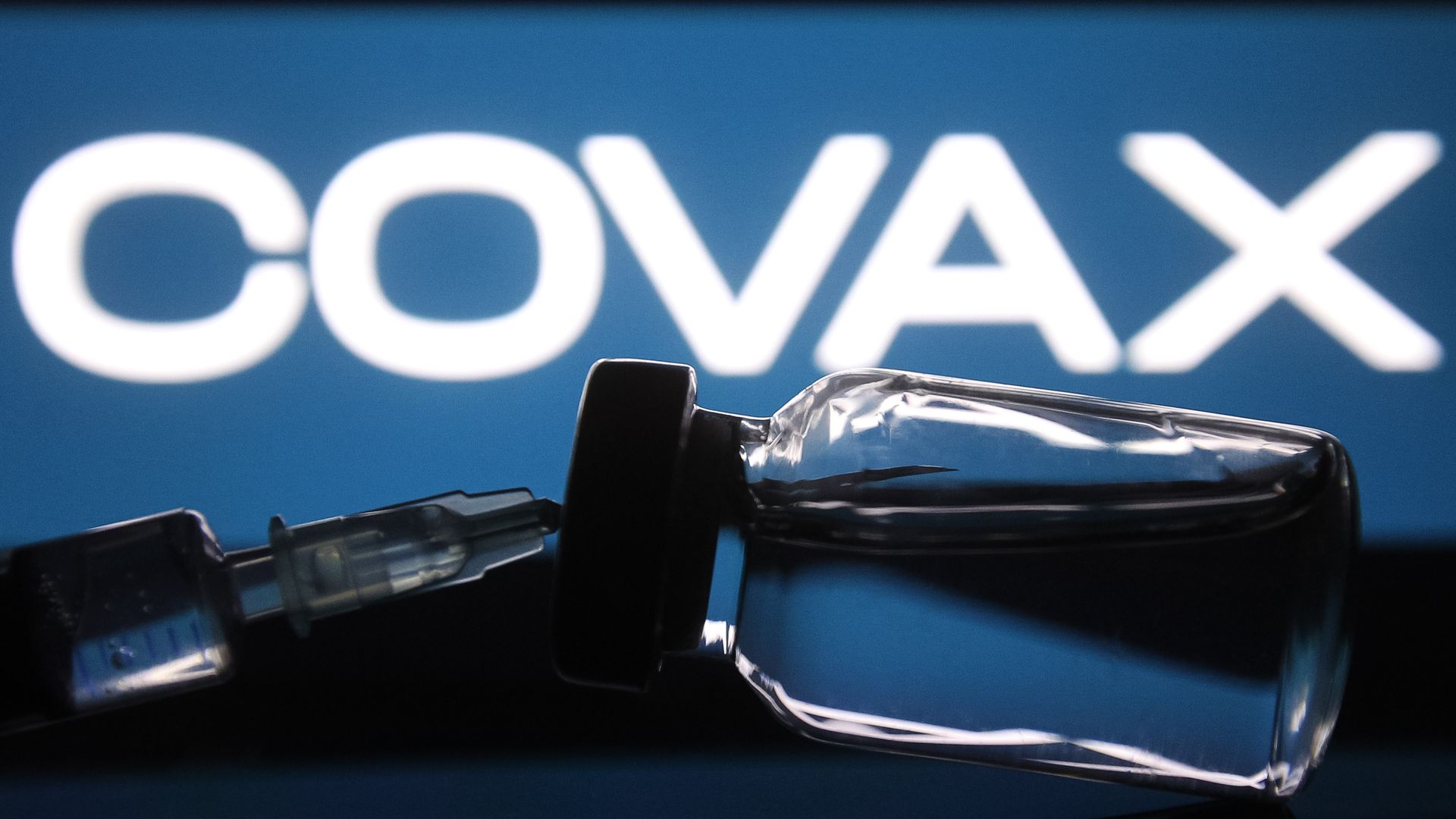 A medical syringe and a vial in front of the COVAX word are seen in this creative illustrative photo. 