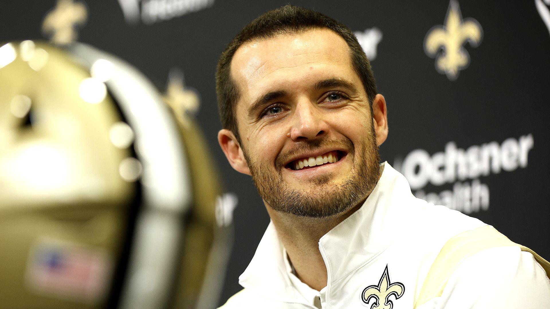 Photo shows Derek Carr smiling at the camera and wearing a shirt with a fleur-de-lis.