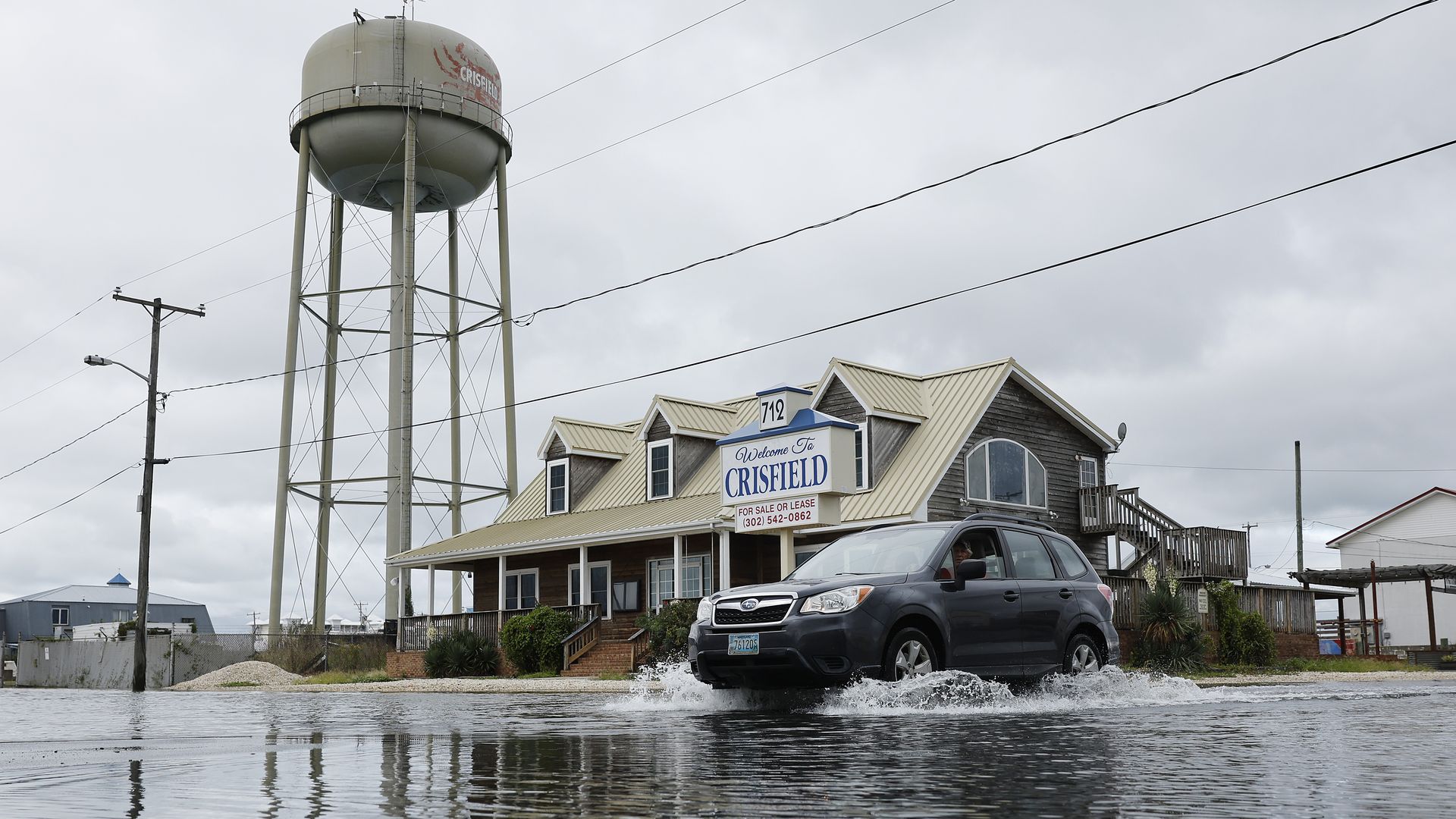 A car drives through a flooded road.