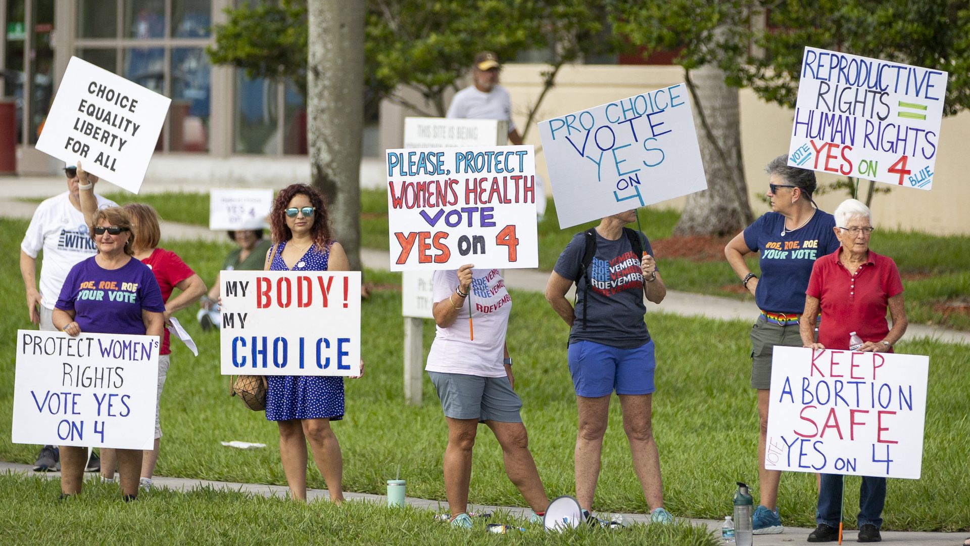 Several people stand on a sidewalk holding signs that say things like, "my body! my choice," "Keep abortion safe Yes on 4" and "pro choice vote yes on 4."
