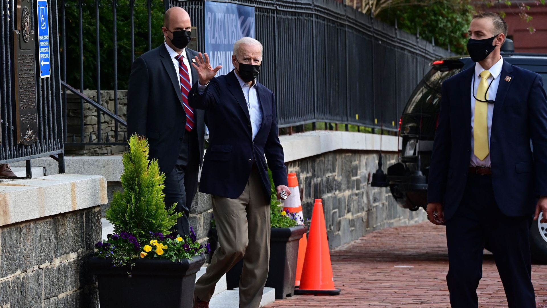 Photo of a masked Joe Biden stepping onto the street and waving