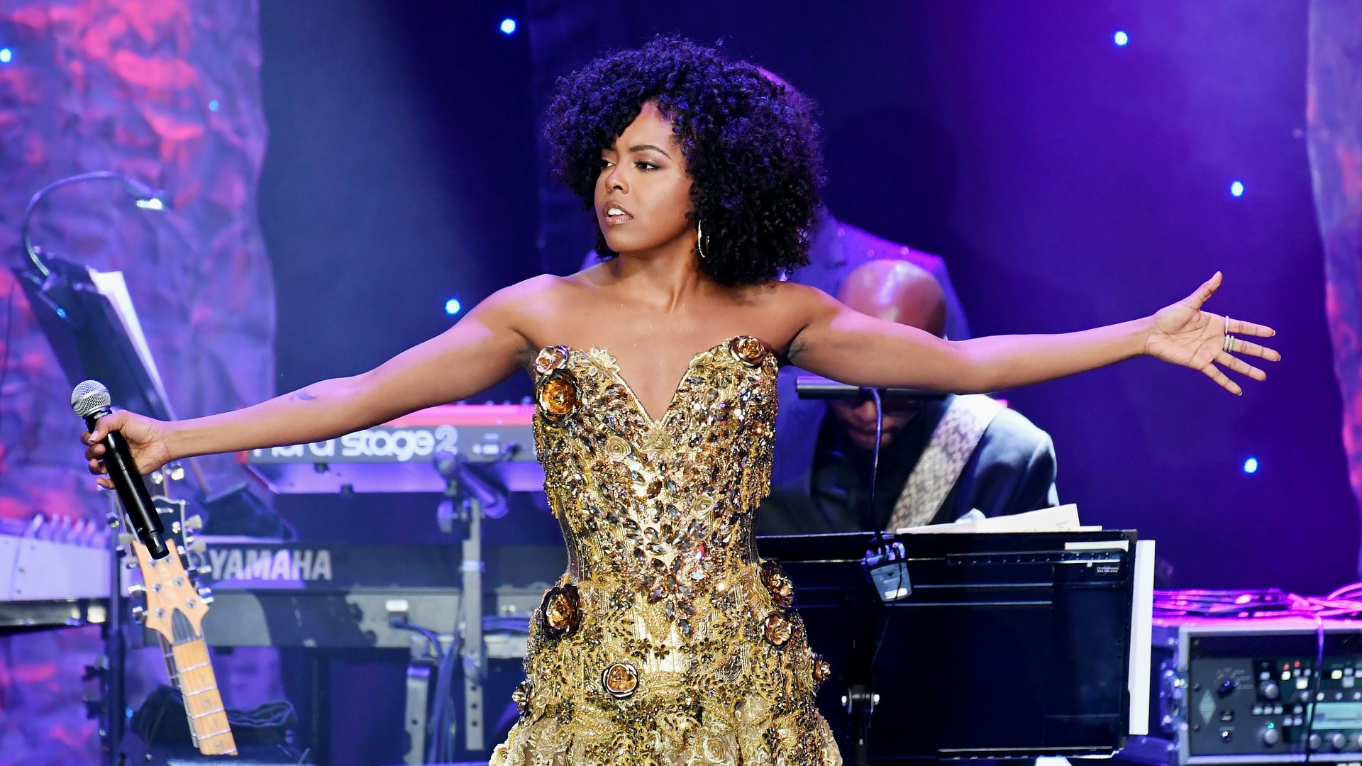 Adrienne Warren performing in a gold dress