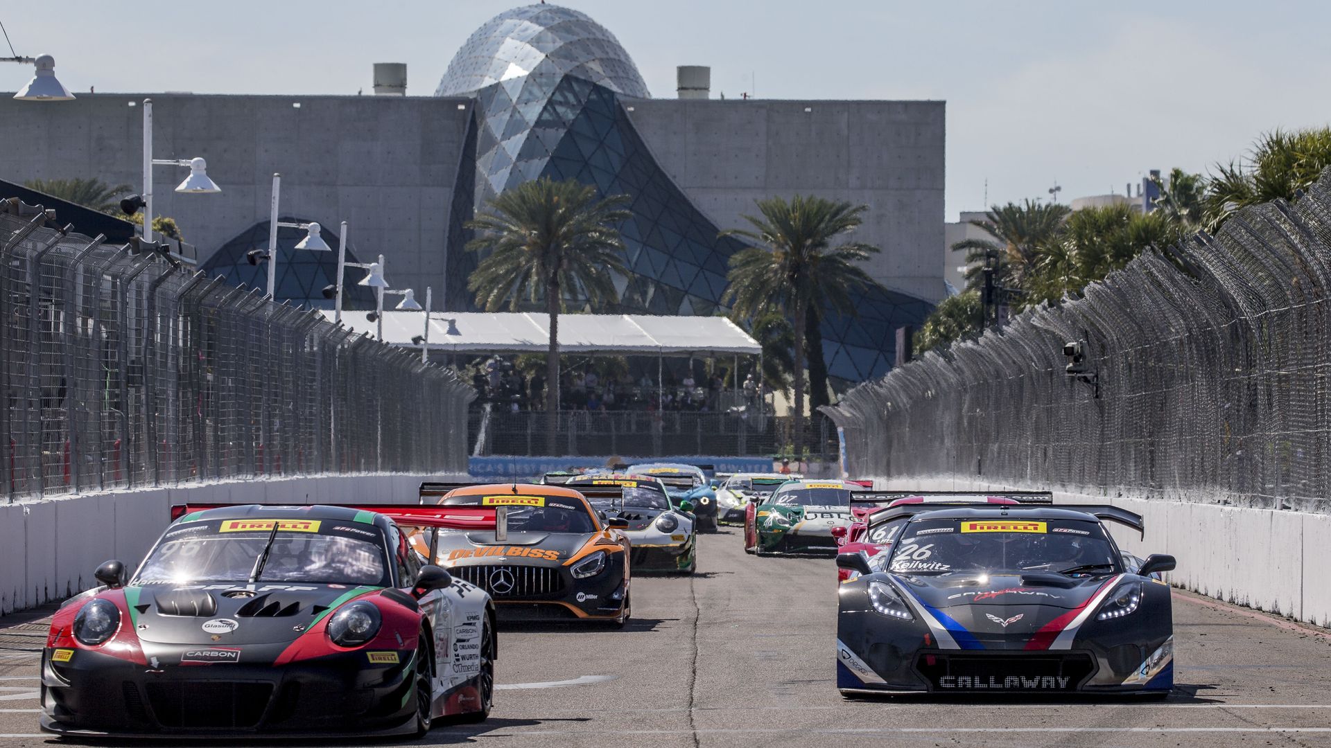 racecars line up on a track with the Dali Museum in the background