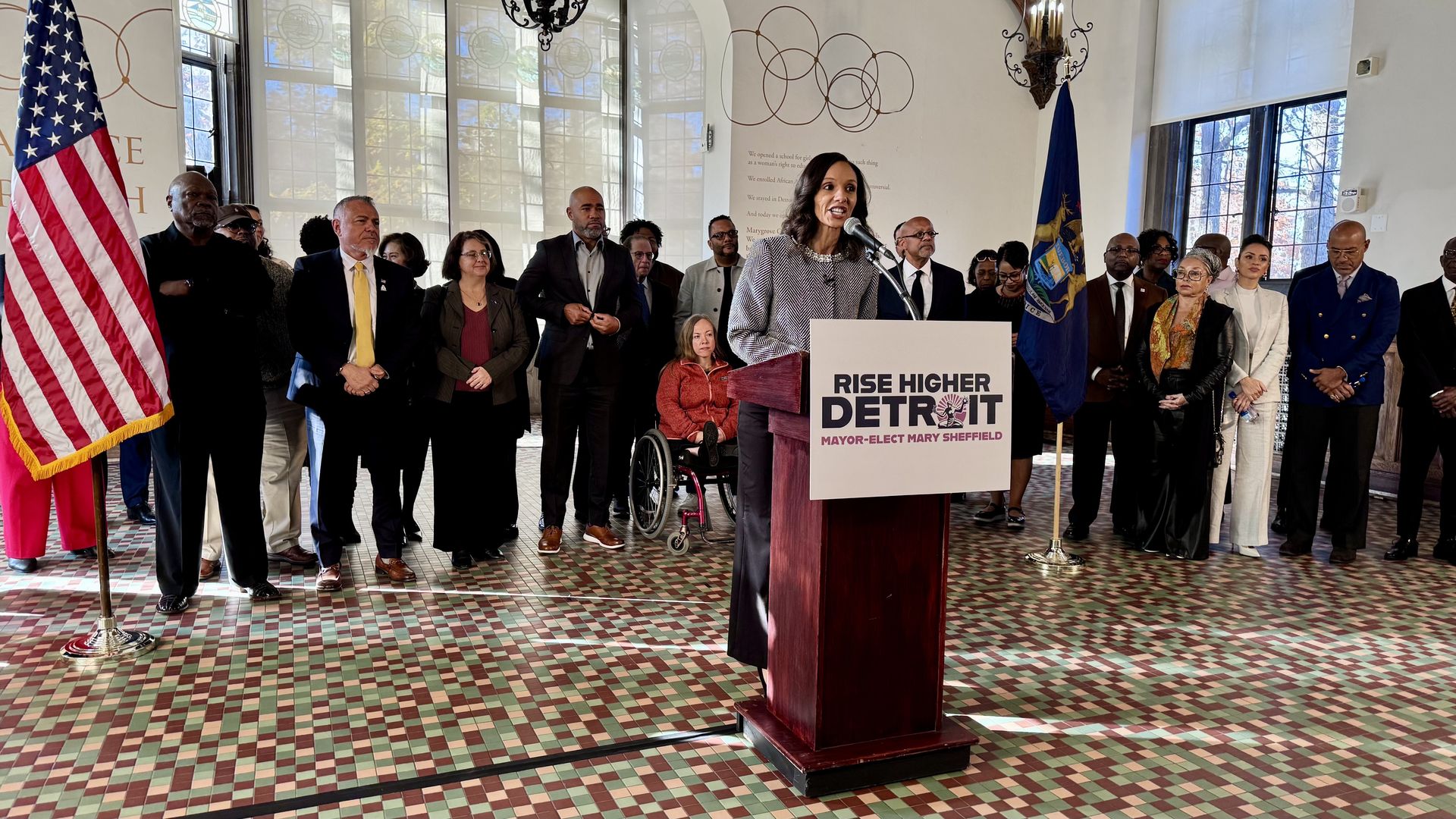 Sheffield stands speaking at a podium in front of a group of people 