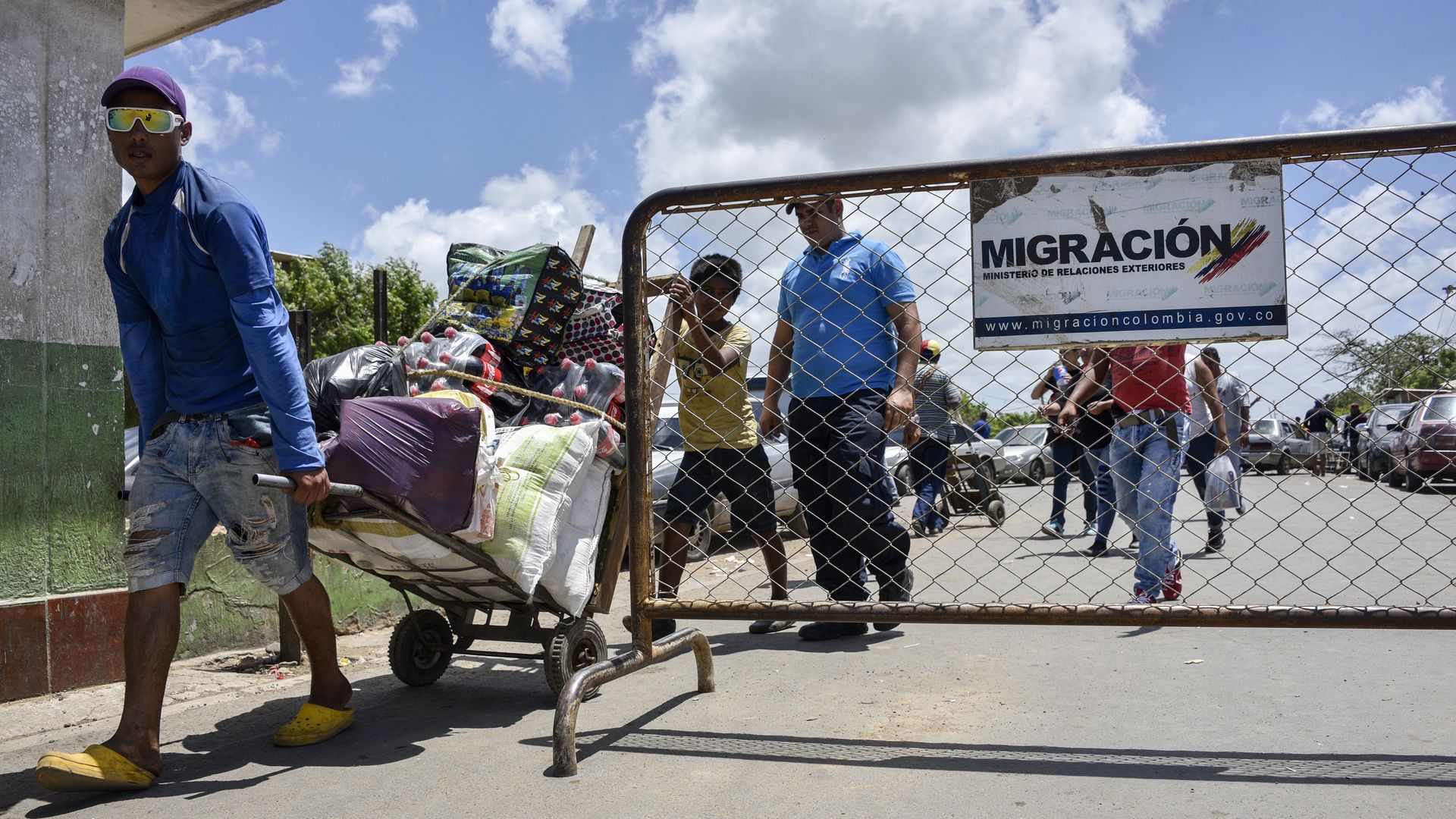 Photo of Venezuelan migrants walking into an enclosed area with belongings