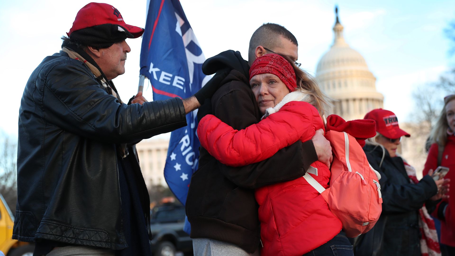 A woman hugs a man while standing in front of the Capitol building