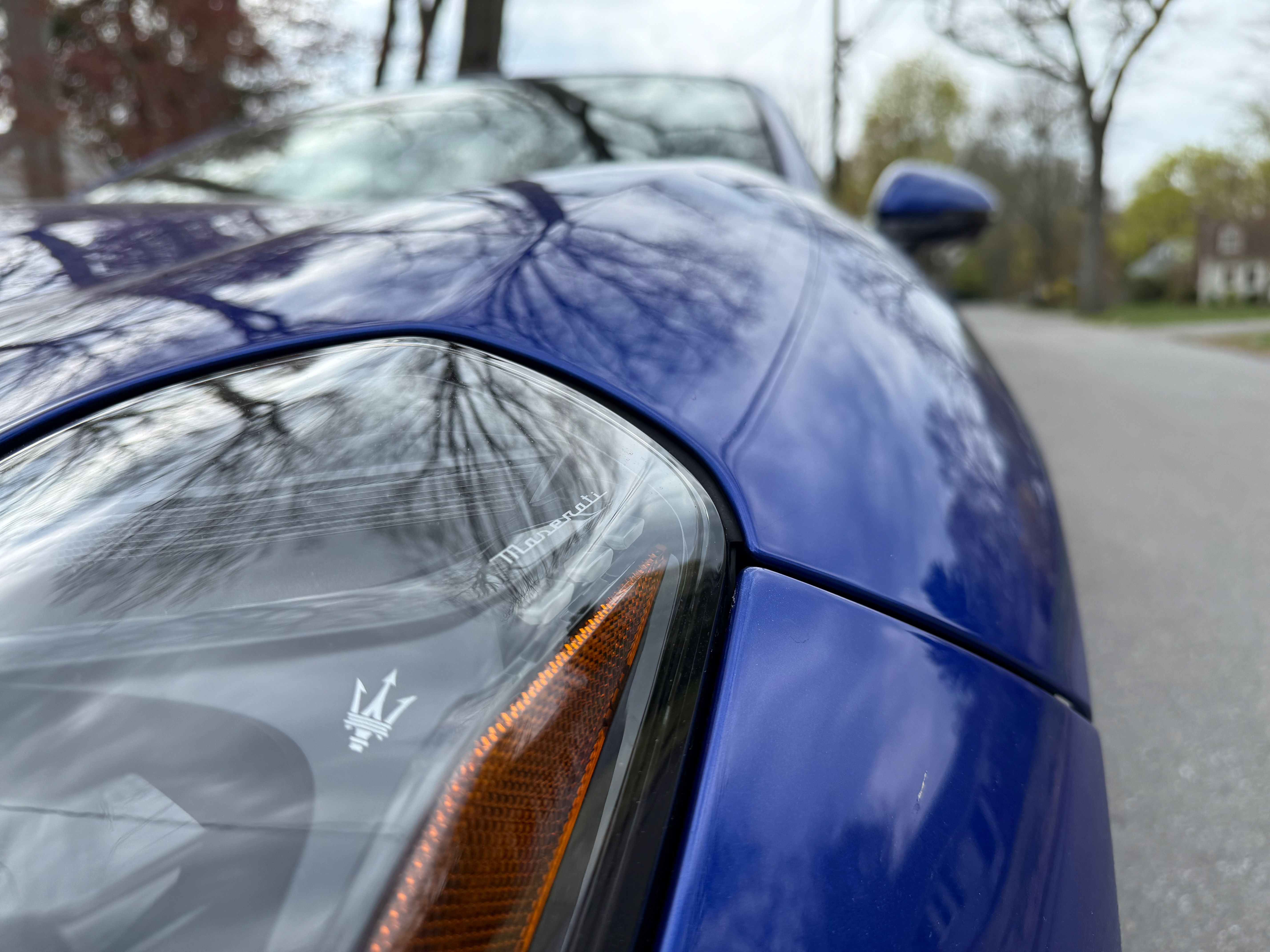 A close-up picture of a headlamp of a Maserati Folgore GranTurismo shows a small Maserati logo within the light structure. 
