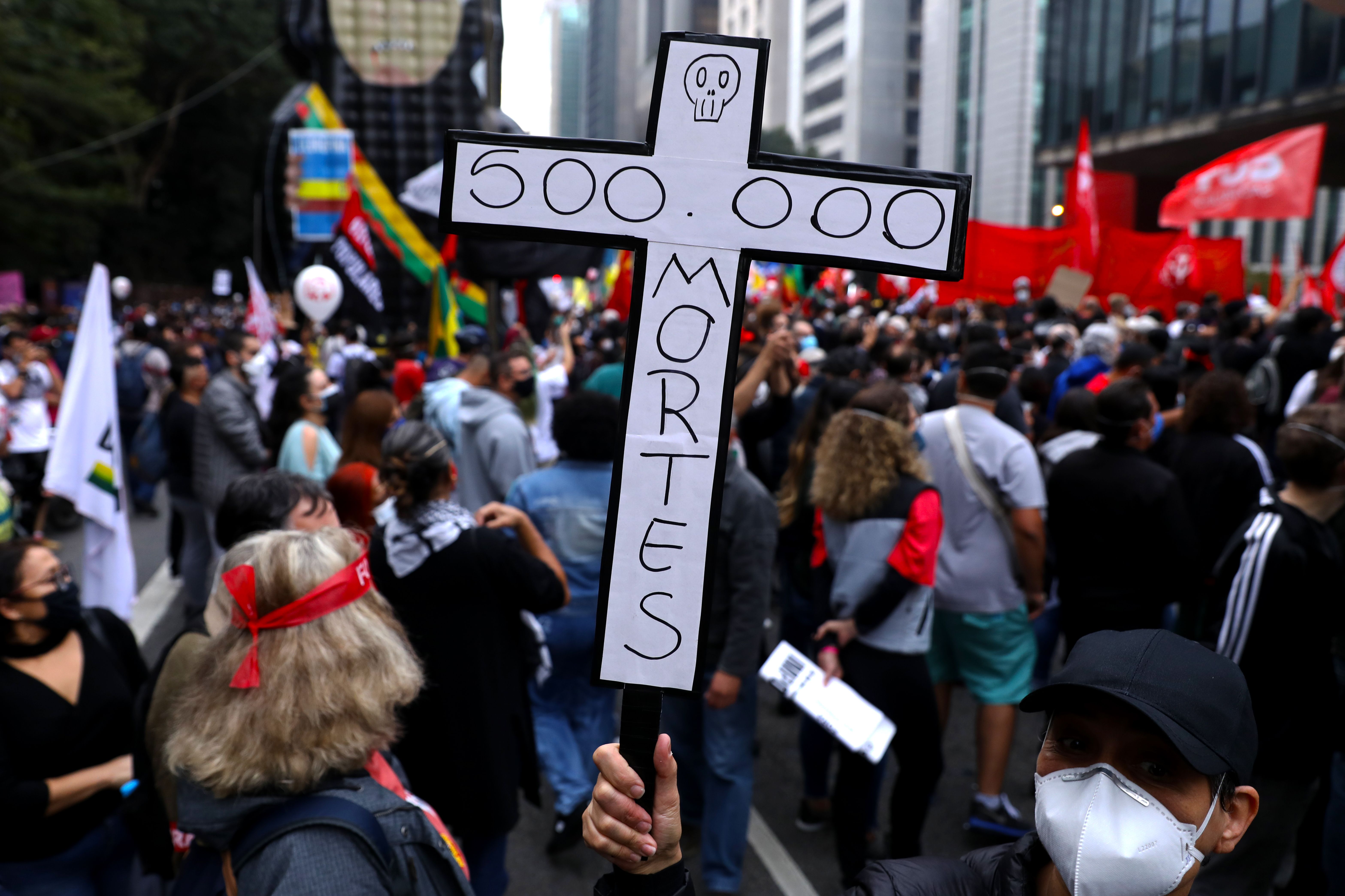 A demonstrator holds a sign in the shape of a cross with the phrase '500,000 deaths' during a protest against Bolsonaro's administration on June 19, 2021 in Sao Paulo, Brazil.