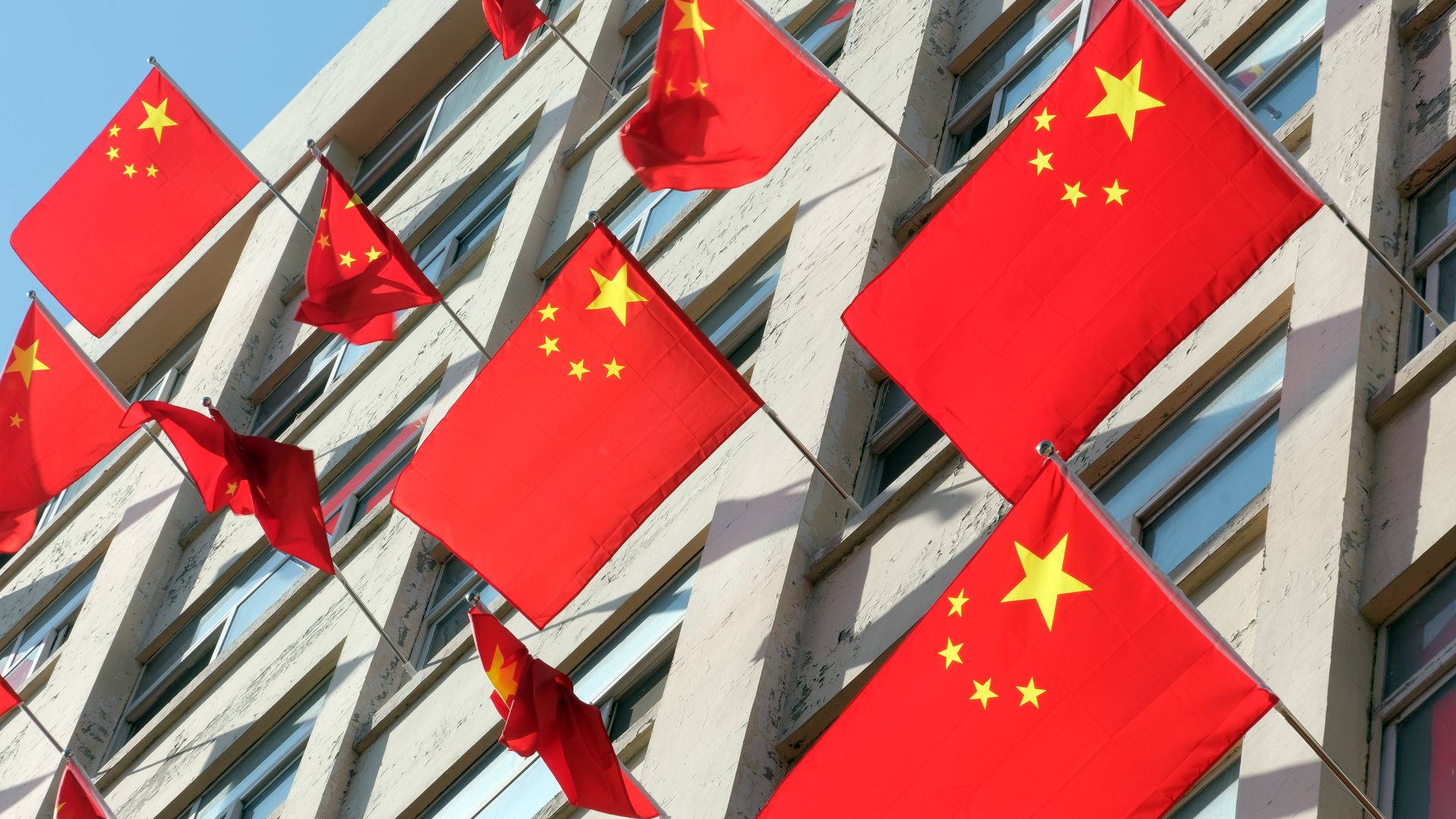 A plethora of Chinese flags sticking out of windows.