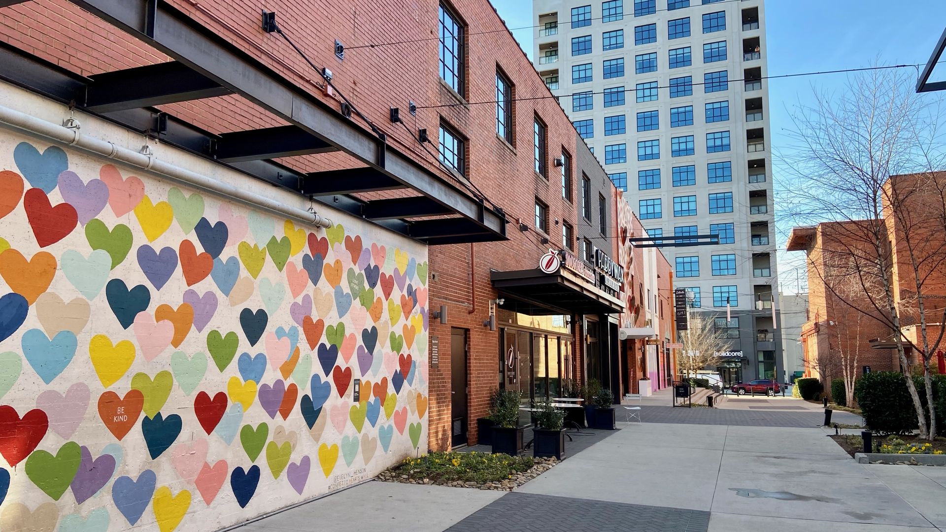 View from alleyway in South End. On the left is the colorful heart mural. In the distance is a tall building.