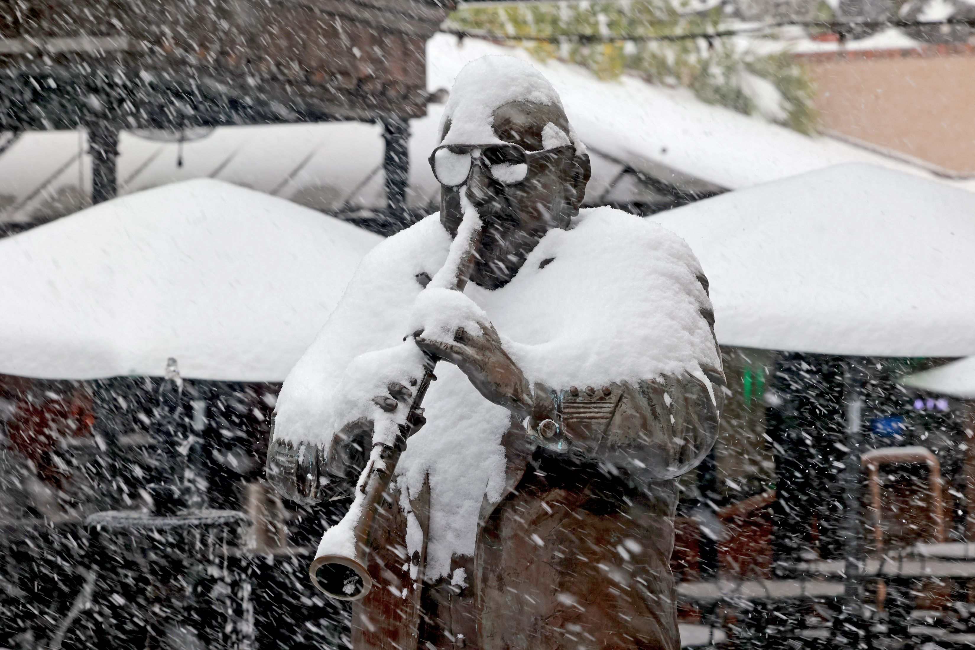 A bronze sculpture is covered in the snow.