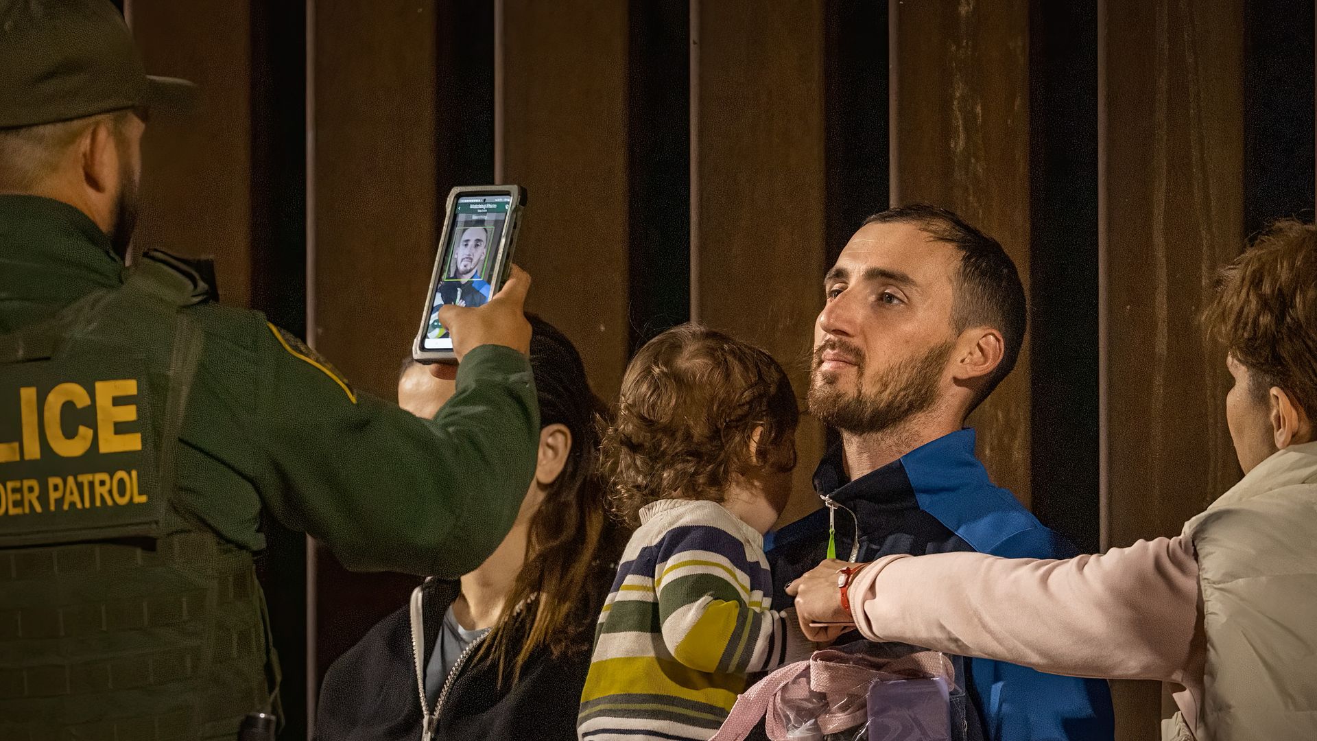 A U.S. Border Patrol agent takes photos of immigrants as they wait to be processed 