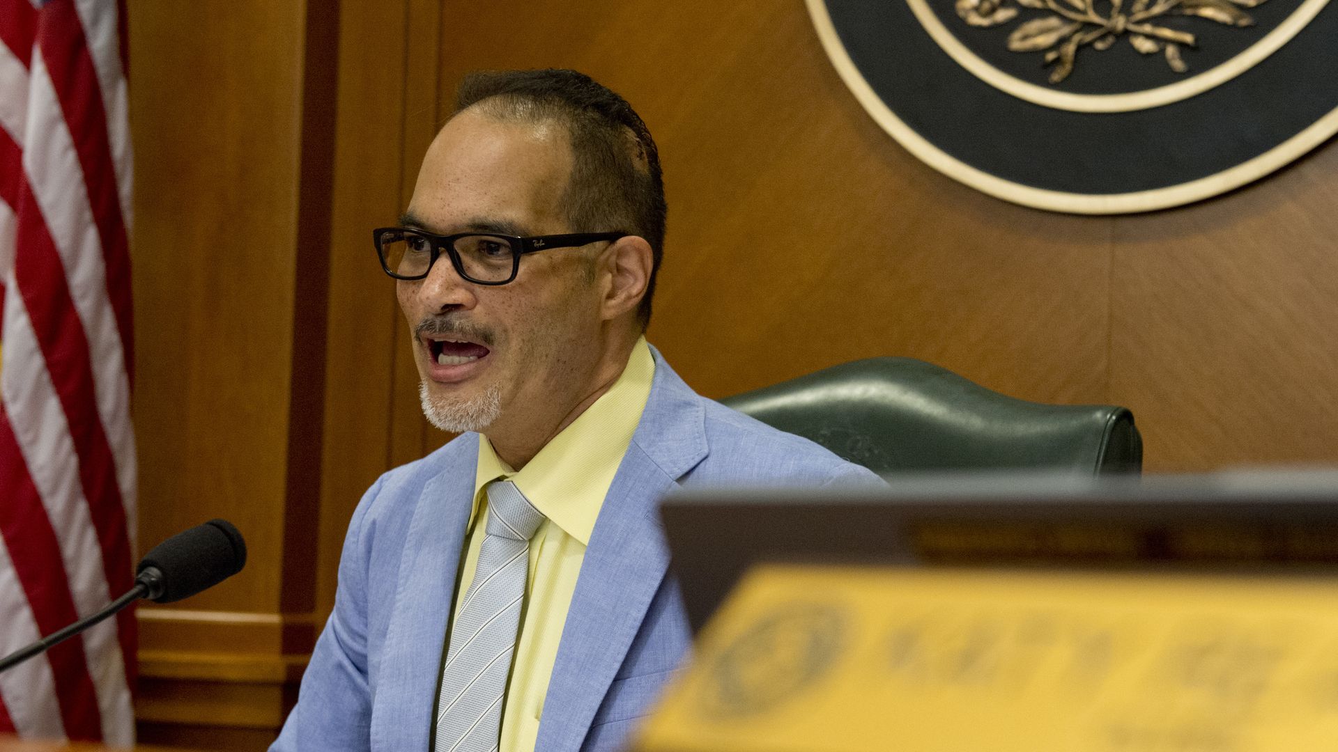 Photo of a man in a blue suit and tie, yellow shirt inside the Texas Capitol.