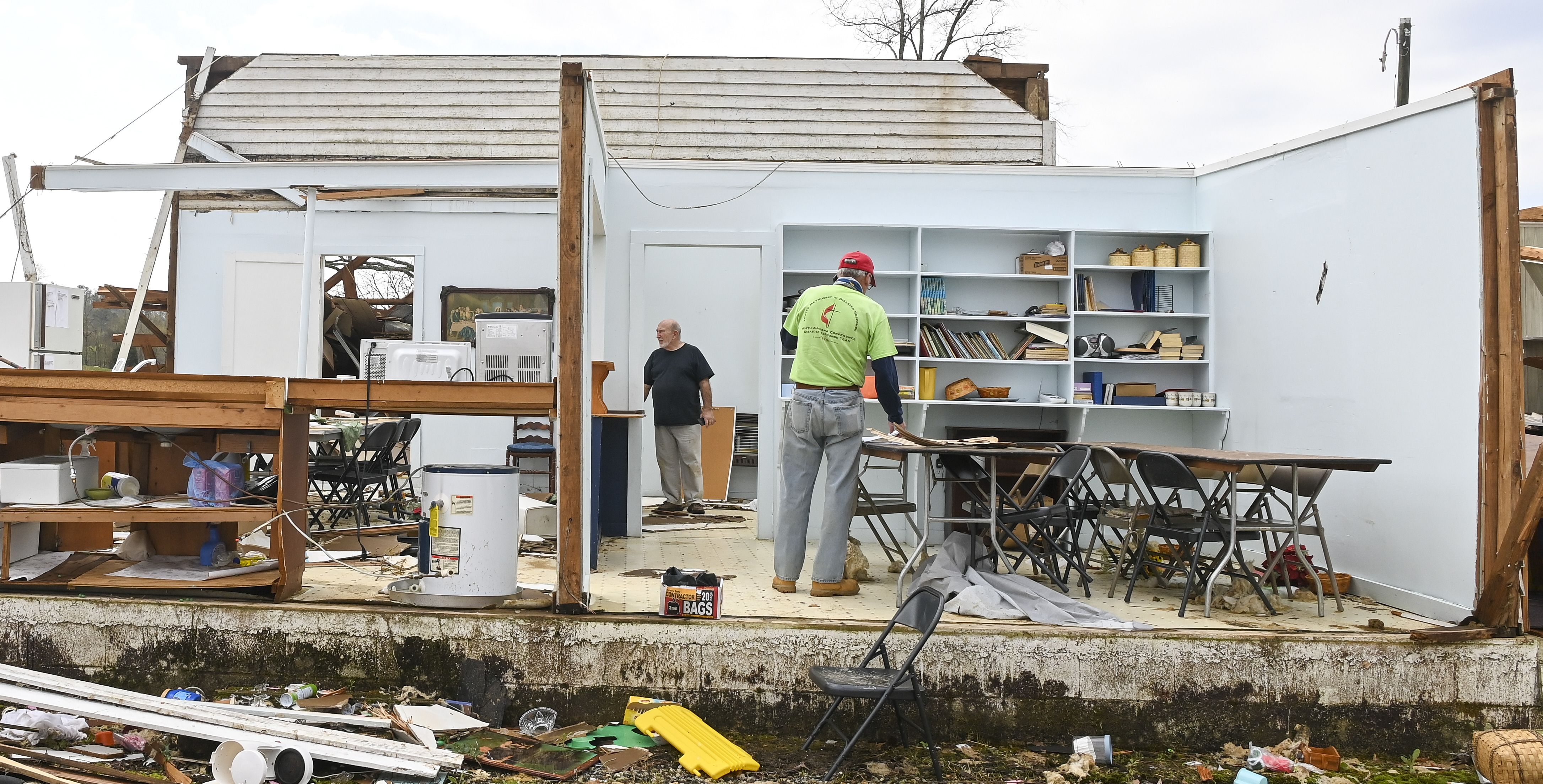 Photo of the inside of a house without its exteriors and two people examining damage from the tornado
