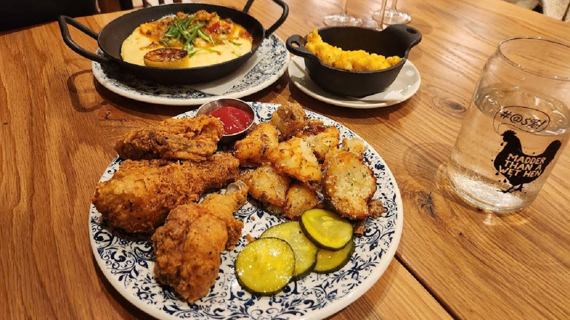 Plates of chicken, shrimp and grits and mac and cheese on a restaurant table. 