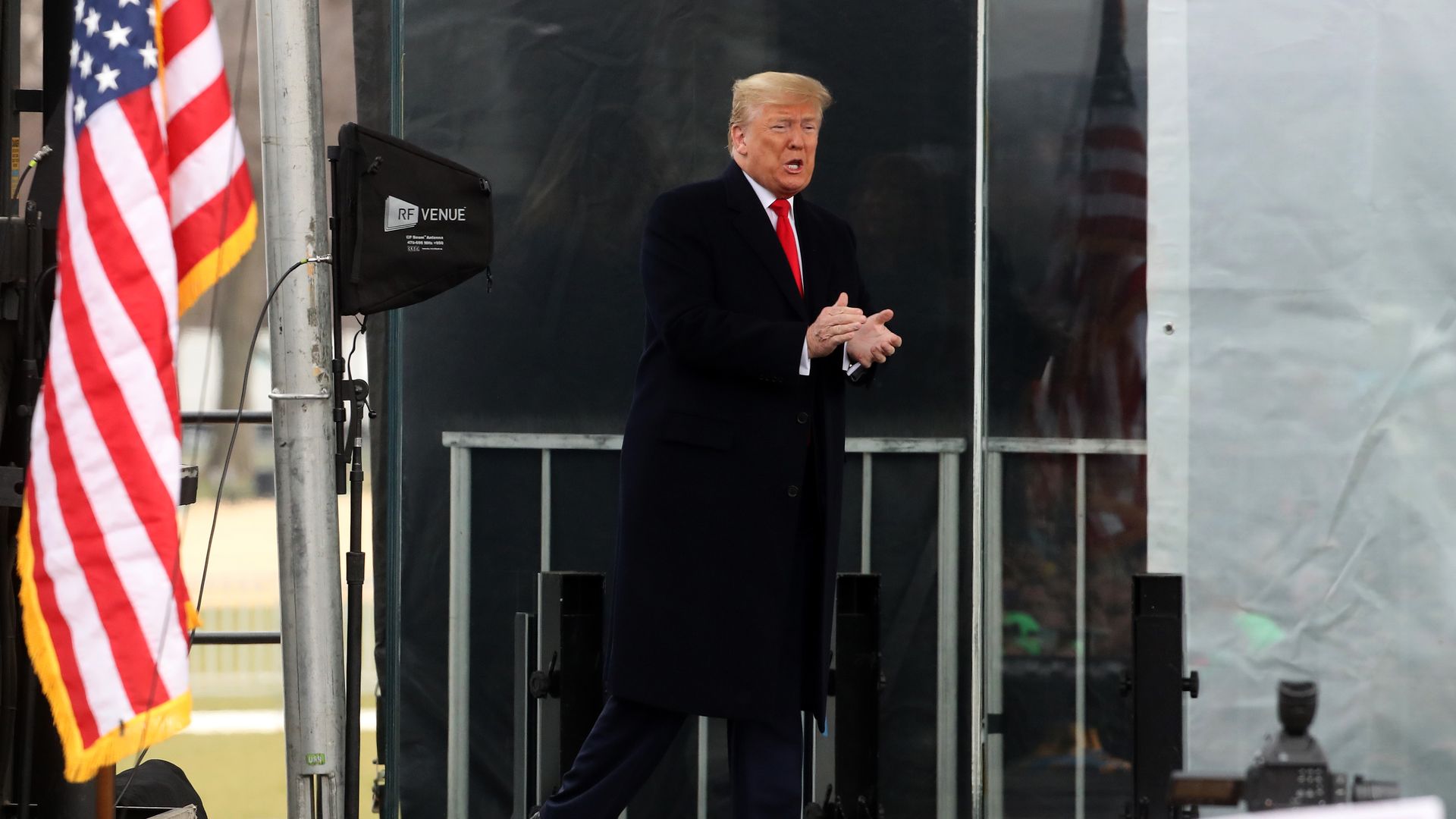 Photo of Trump walking on stage with a flag on the side.