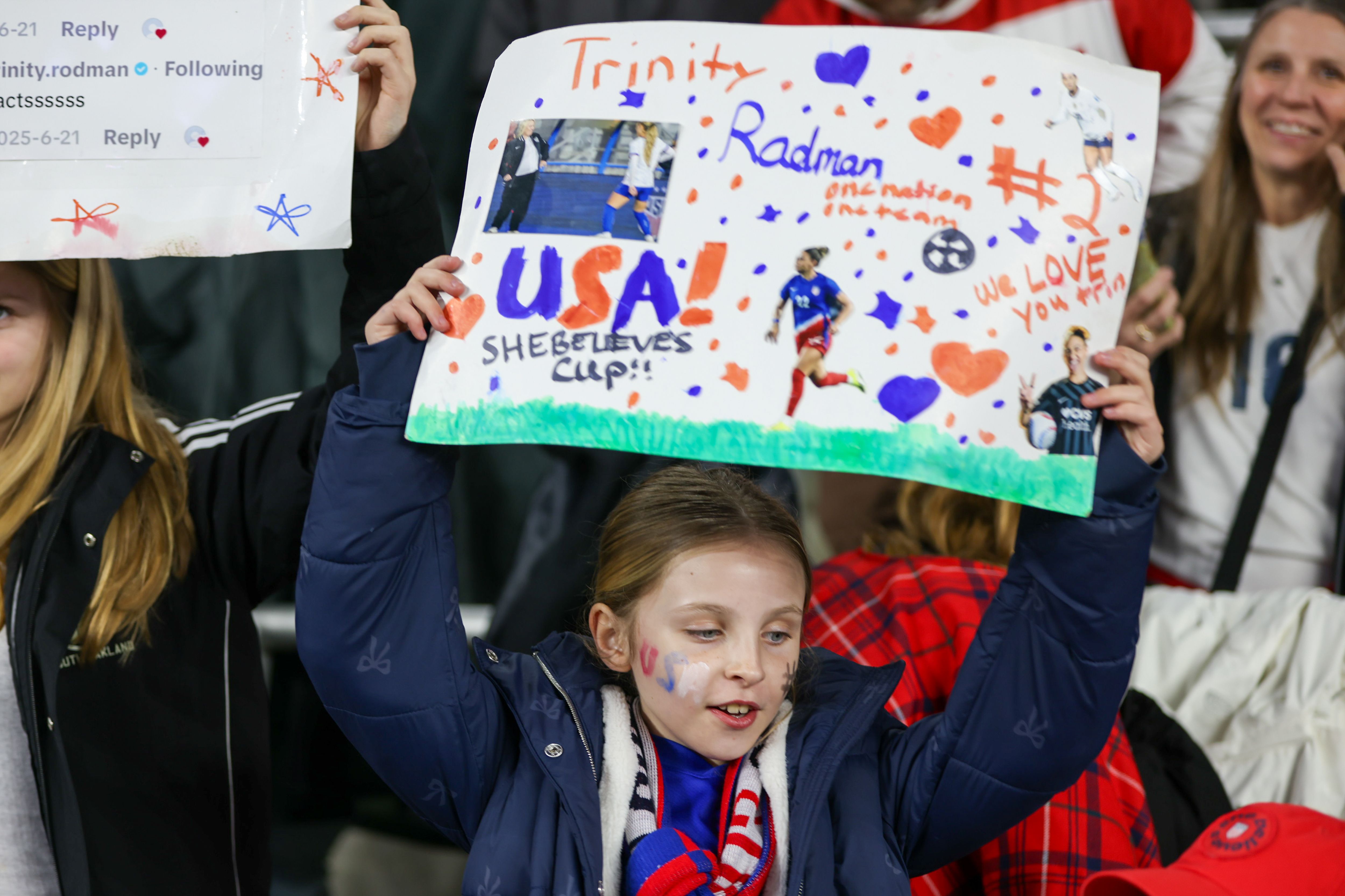 A girl cheering the U.S. Women's National Team holds up a sign supporting Trinity Rodman and the team