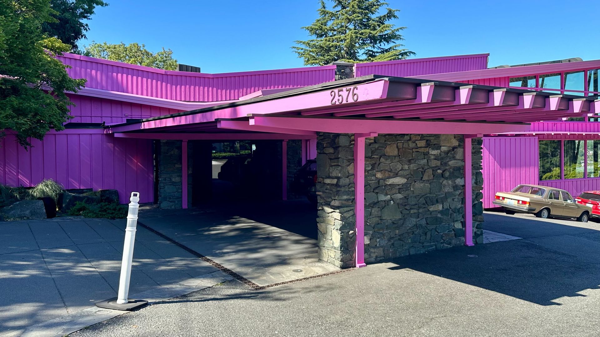 A midcentury style restaurant is painted bright pink with a blue sky behind.