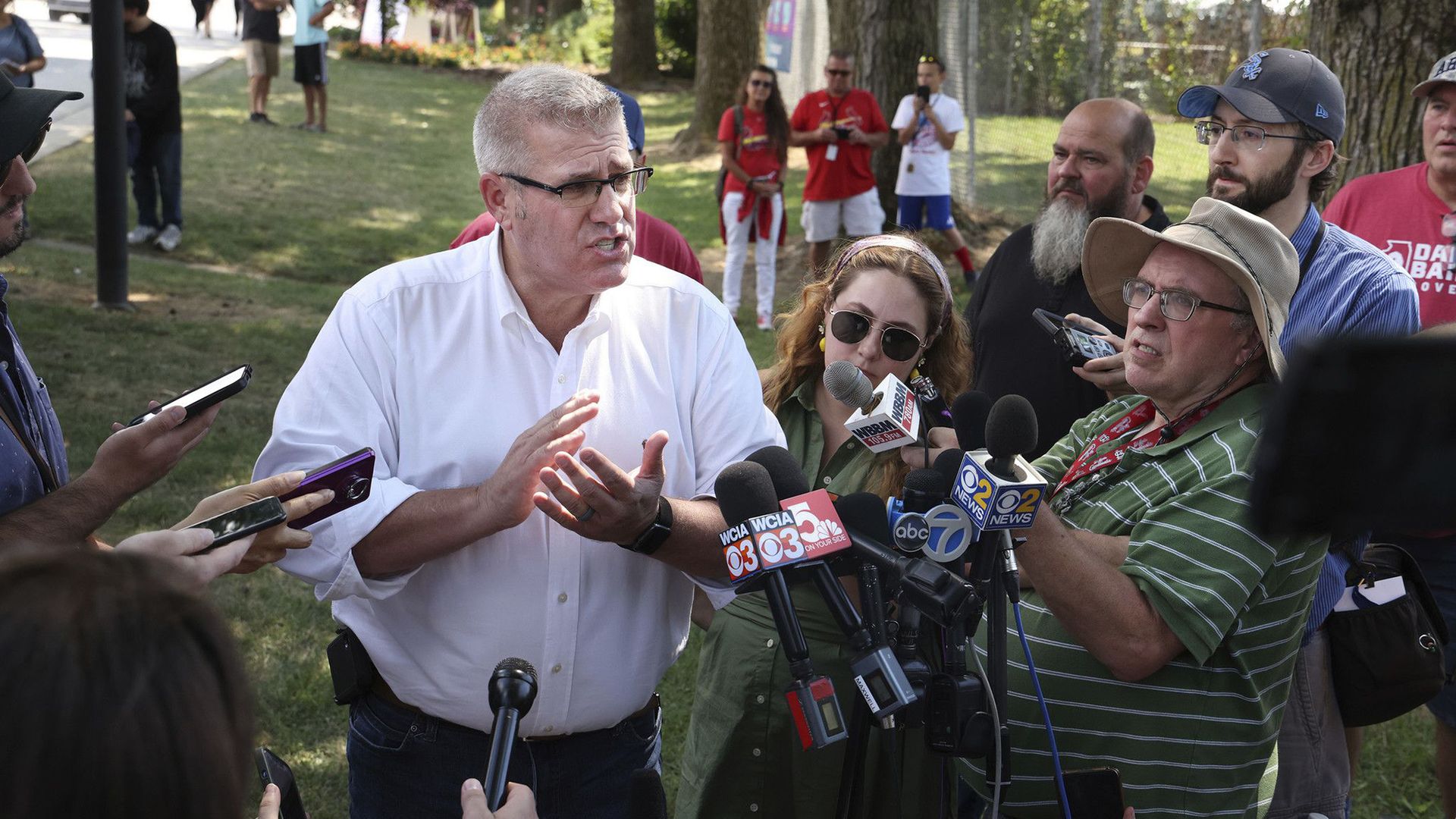 Photo of a man talking in front of several microphones