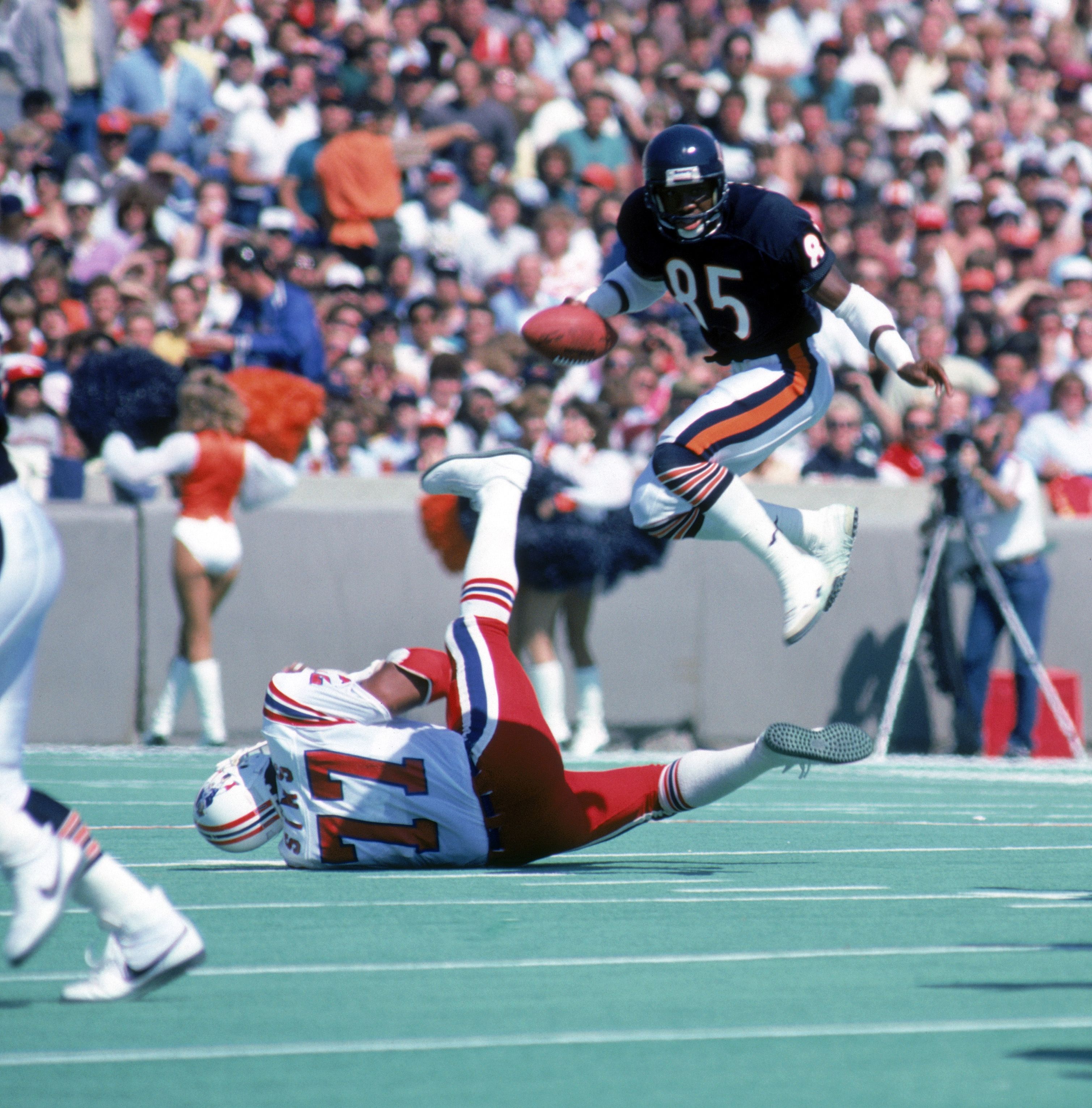 Football player hops over another football player during a game. 