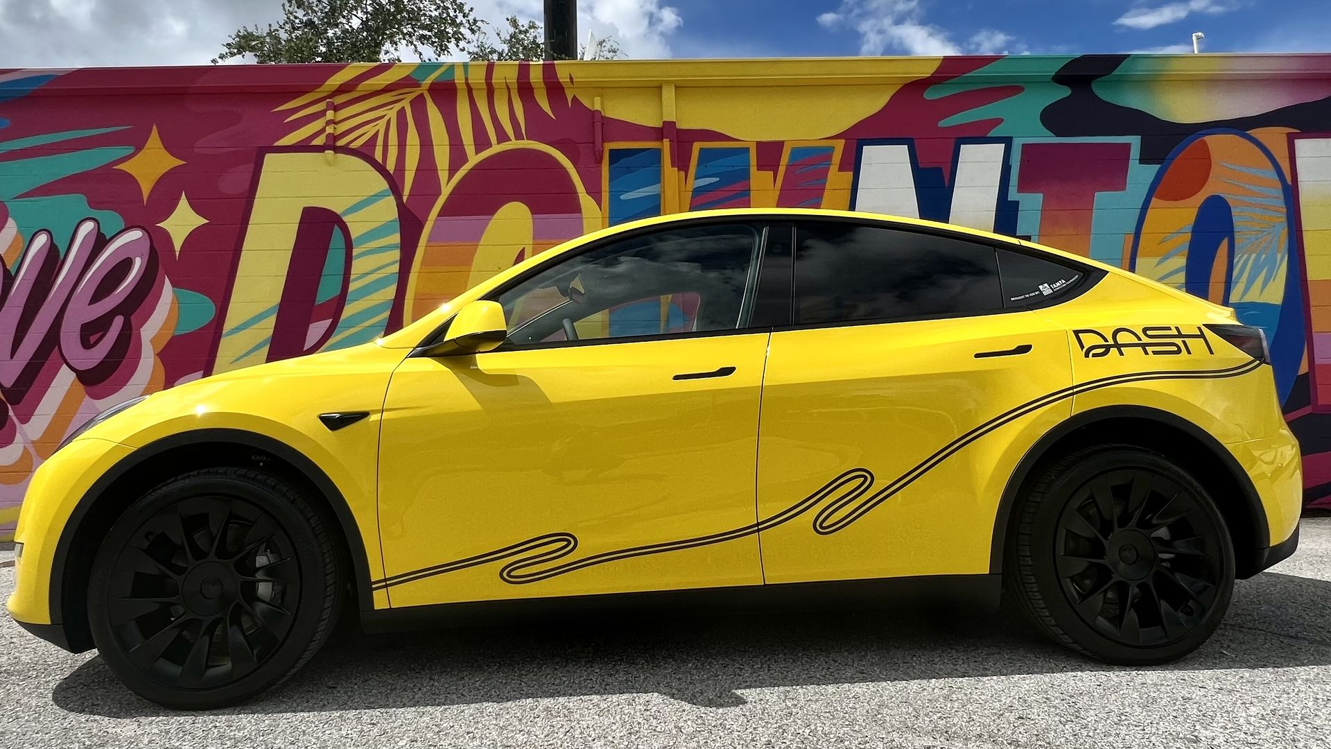 a yellow and black DASH vehicle in front of the Tampa Downtown Partnership building's colorful mural