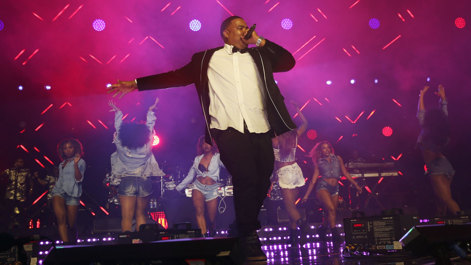 Image show Choppa singing on stage with dancers behind him.