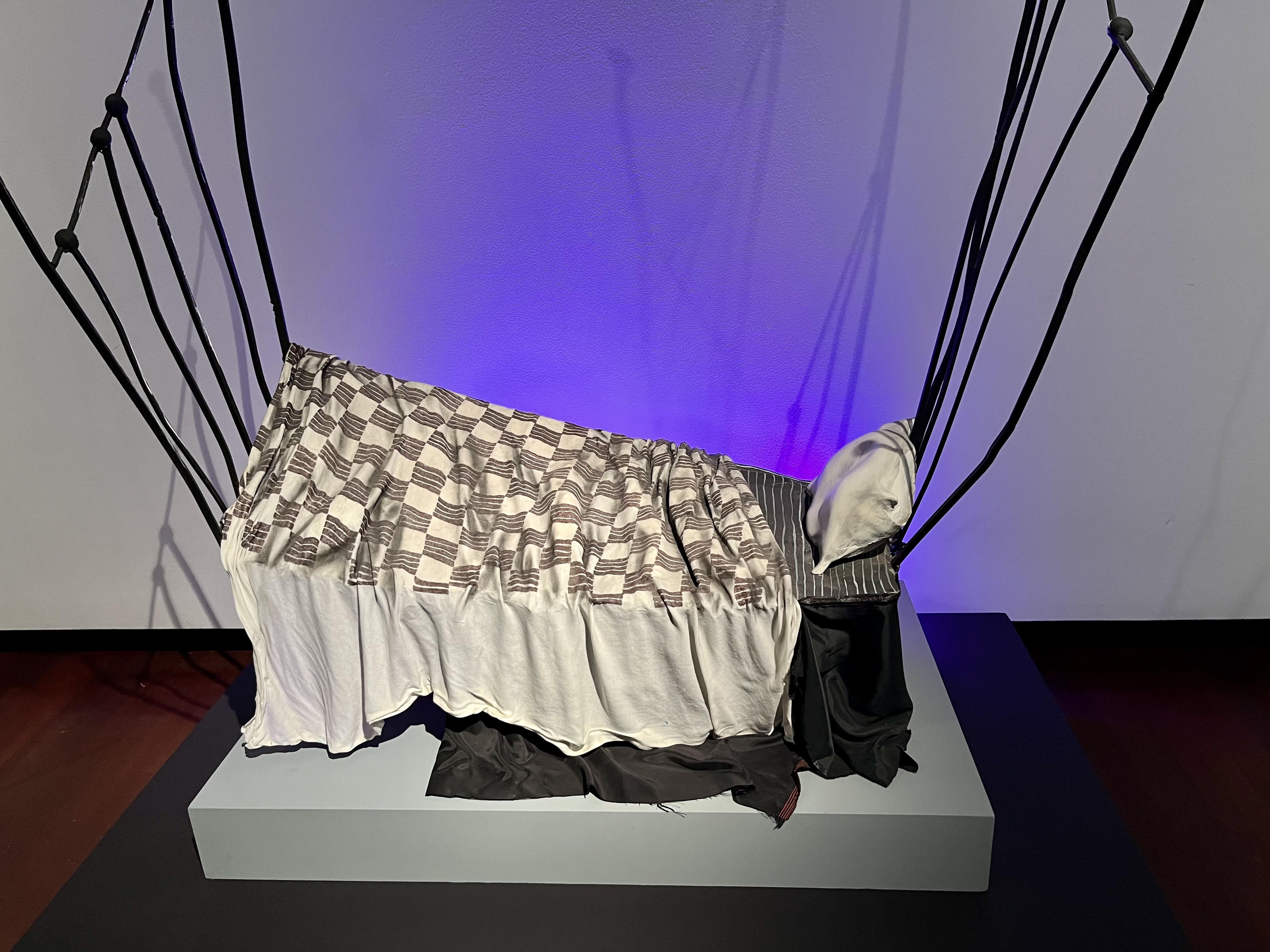 A lopsided bed with a checkered cover and tall, thin bed frame lines.