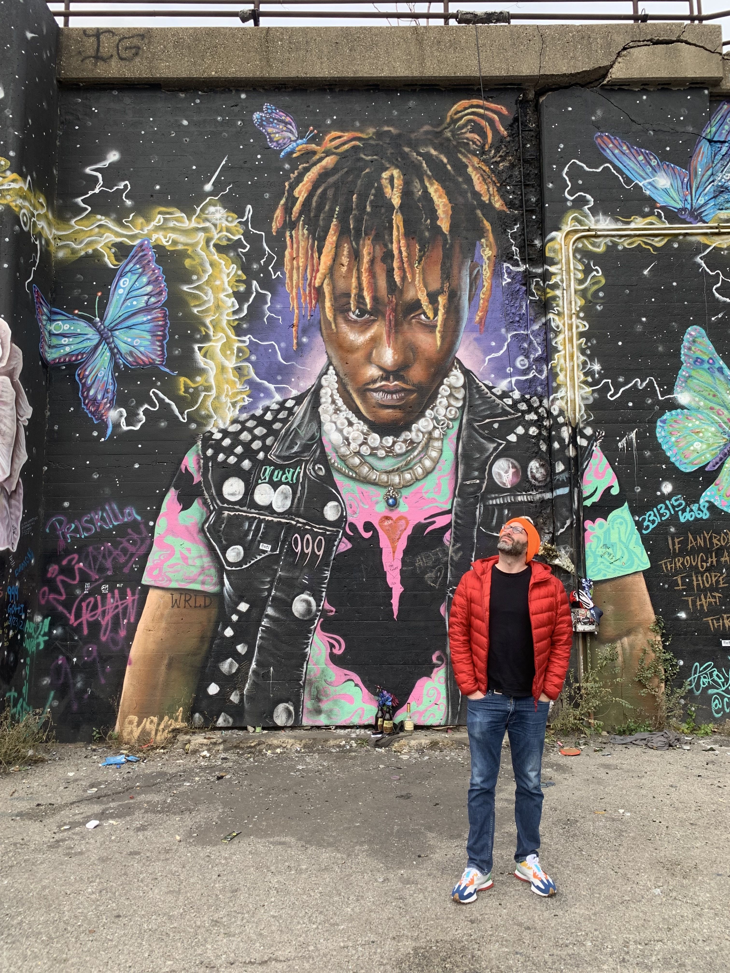 A man stands in front of a mural. 