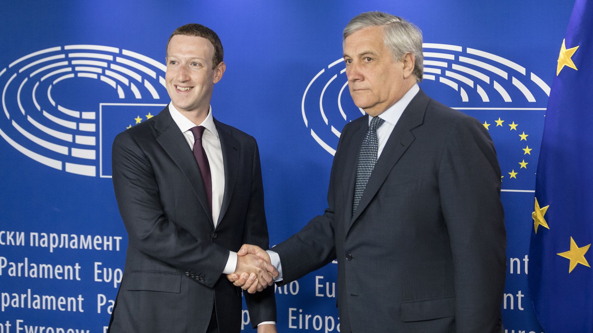 Mark Zuckerberg, smiling, shakes the hand of an unsmiling lawmaker in the EU