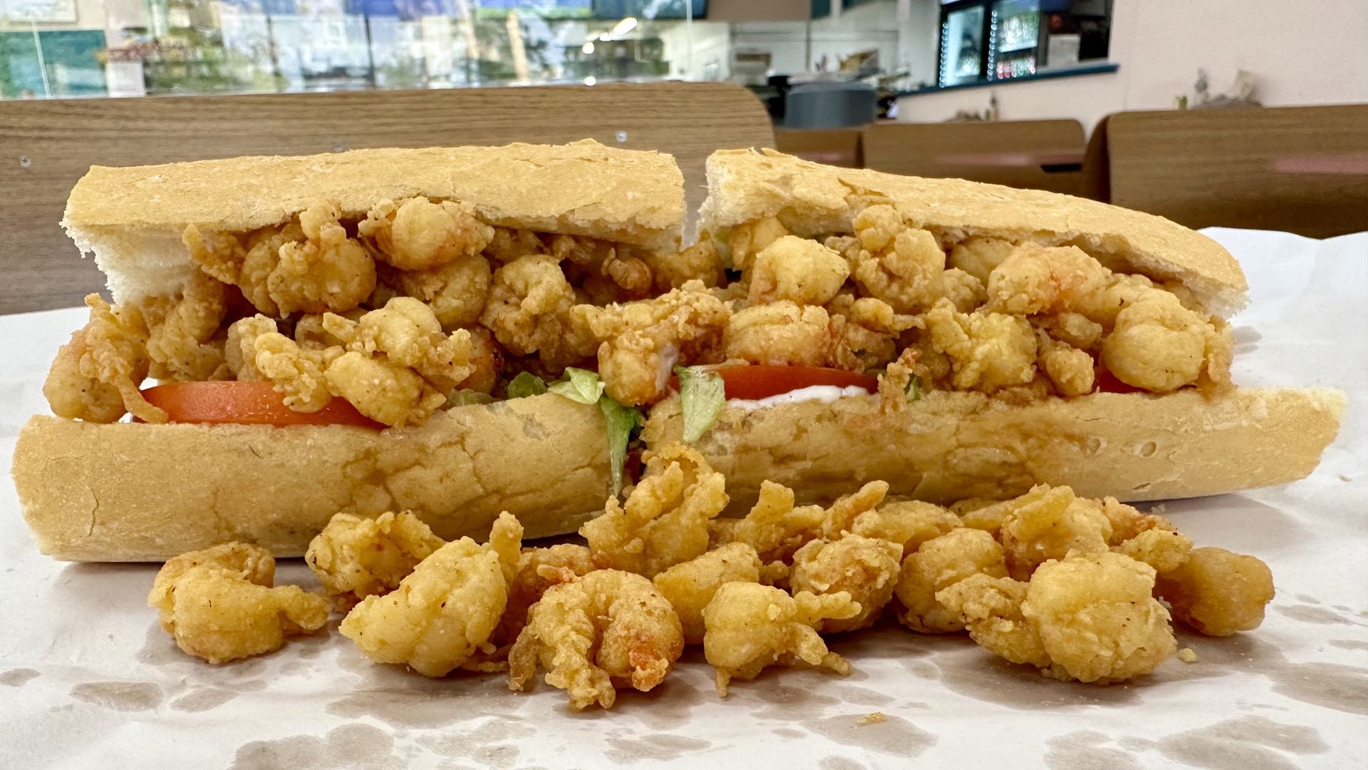 Photo shows fried crawfish tails spilling out of a poboy.