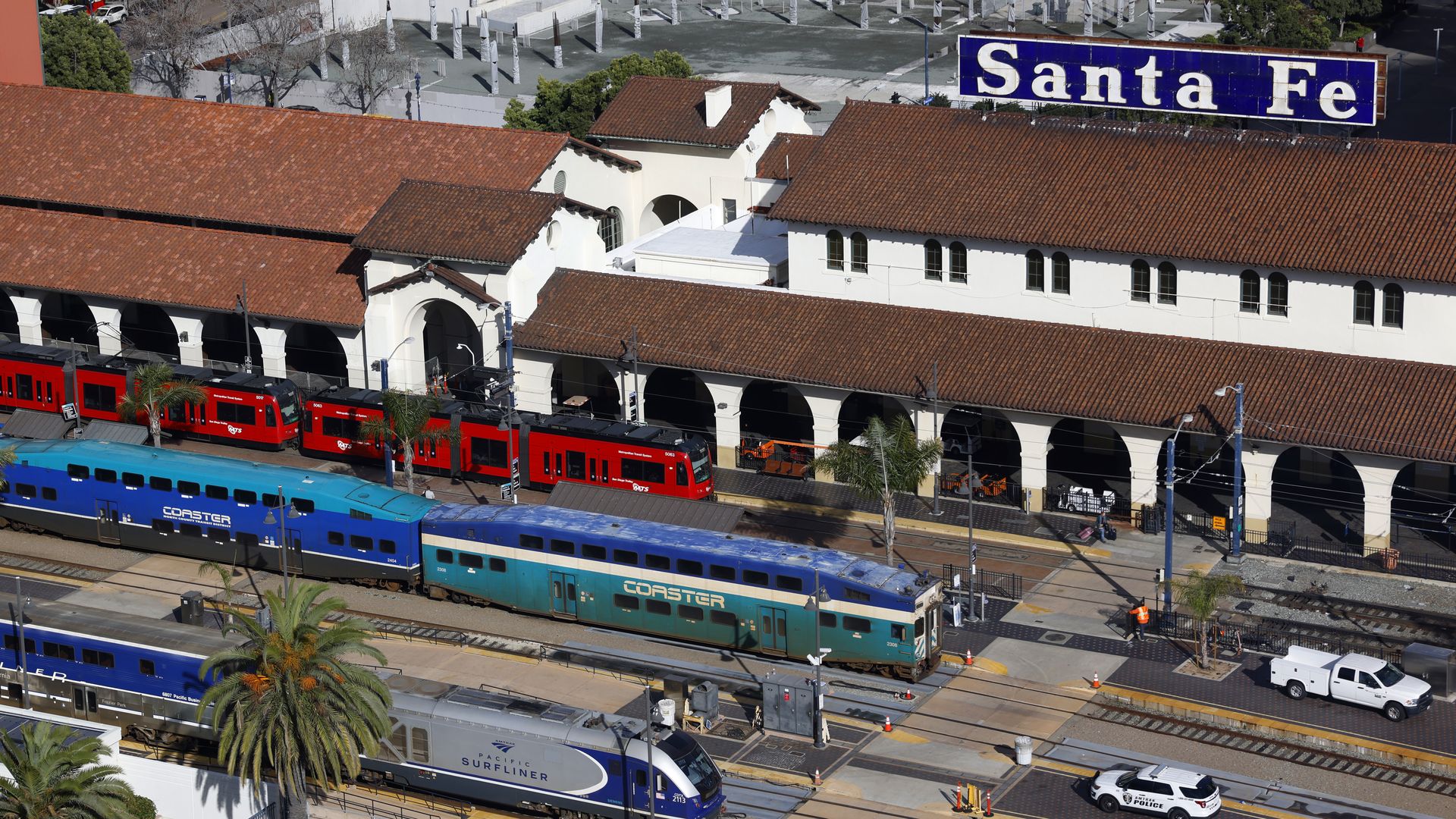 An overhead shot of Santa Fe depot, with a Trolley, Coaster and Surfliner train on the tracks.