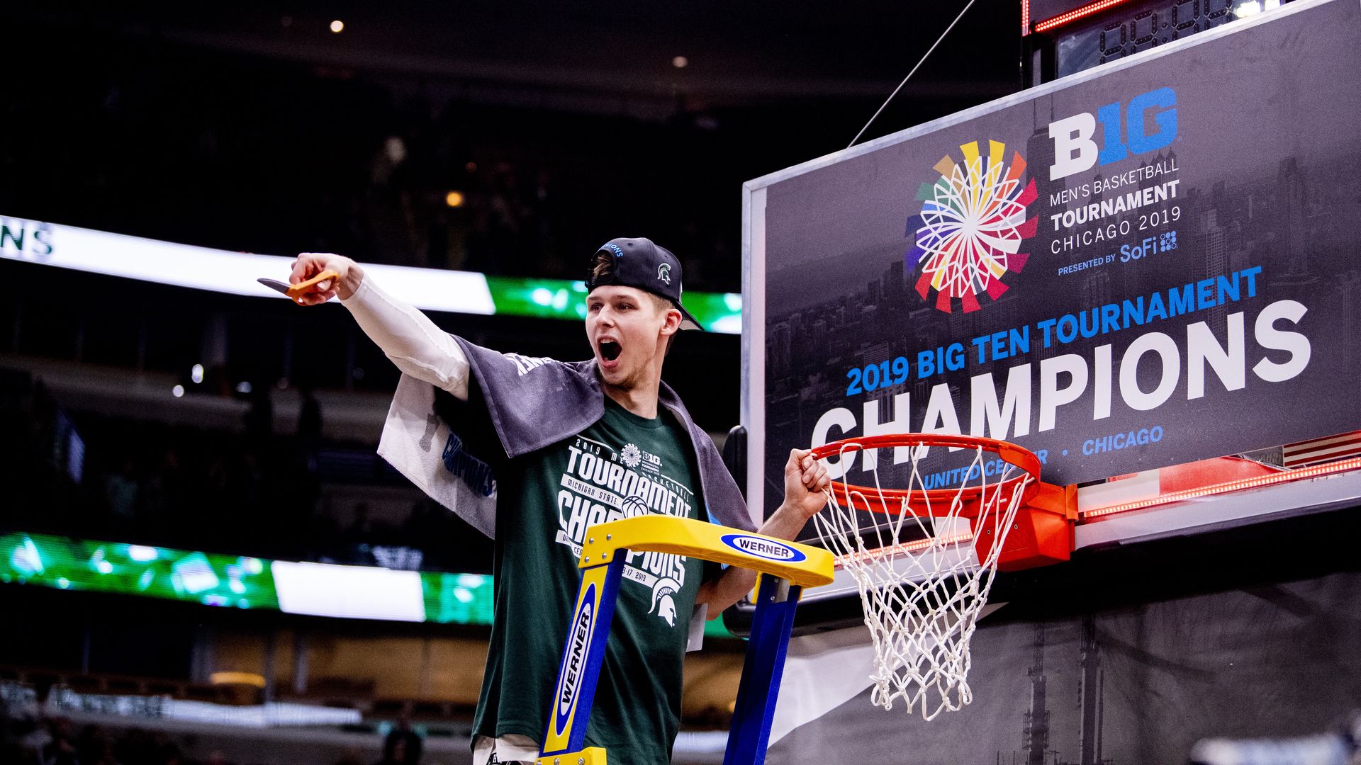 Photo of a basketball player cutting down a net 