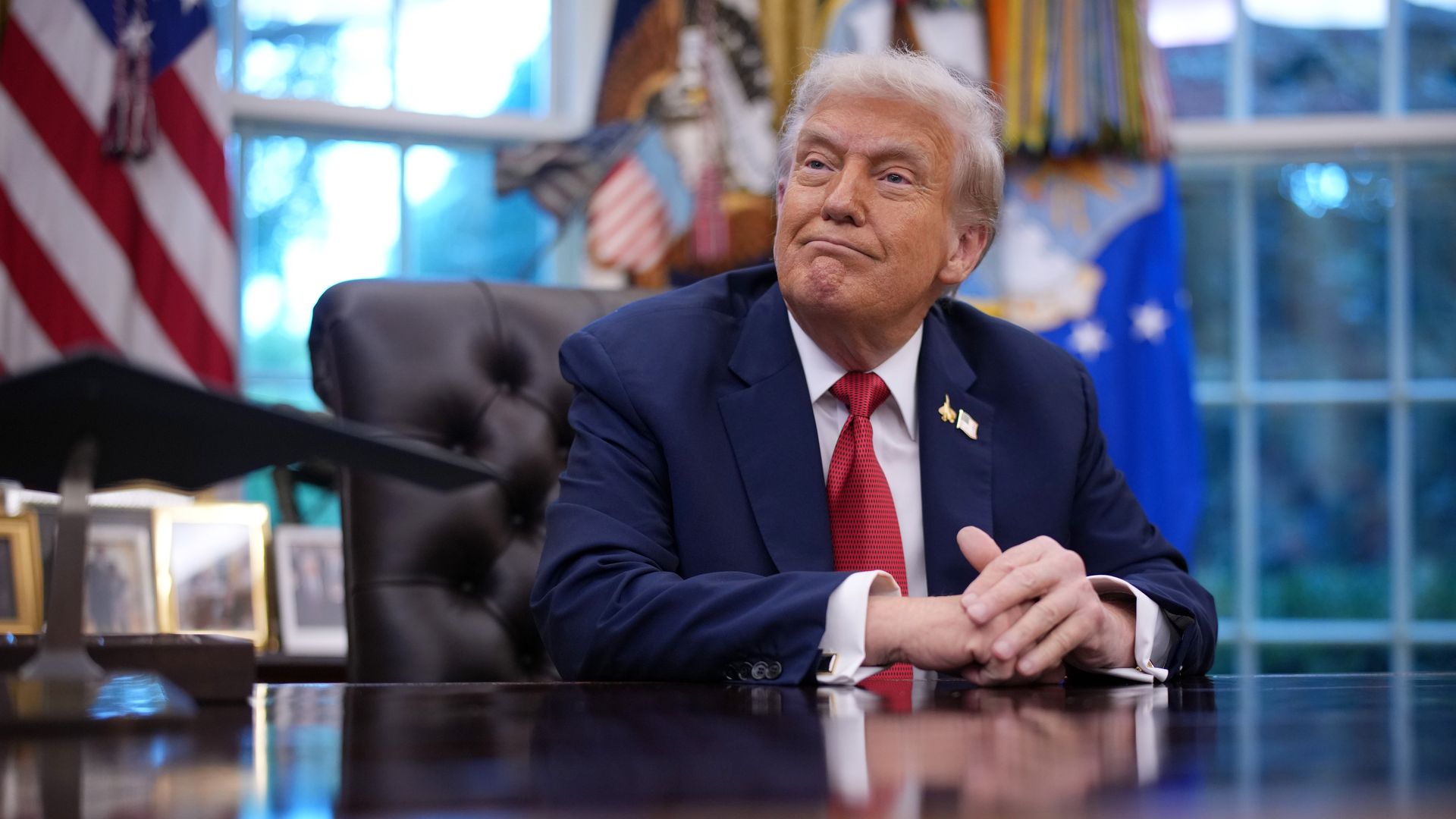 Trump sits at desk, someone hands him a folder