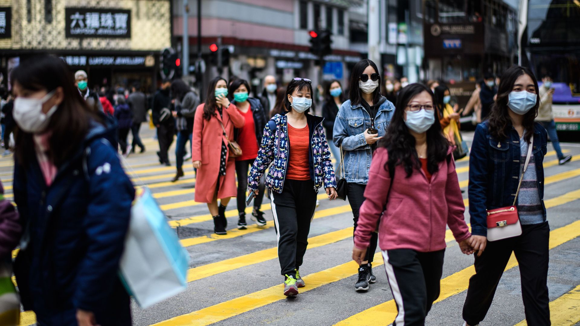 Pedestrians wearing face masks cross a road in Hong Kong