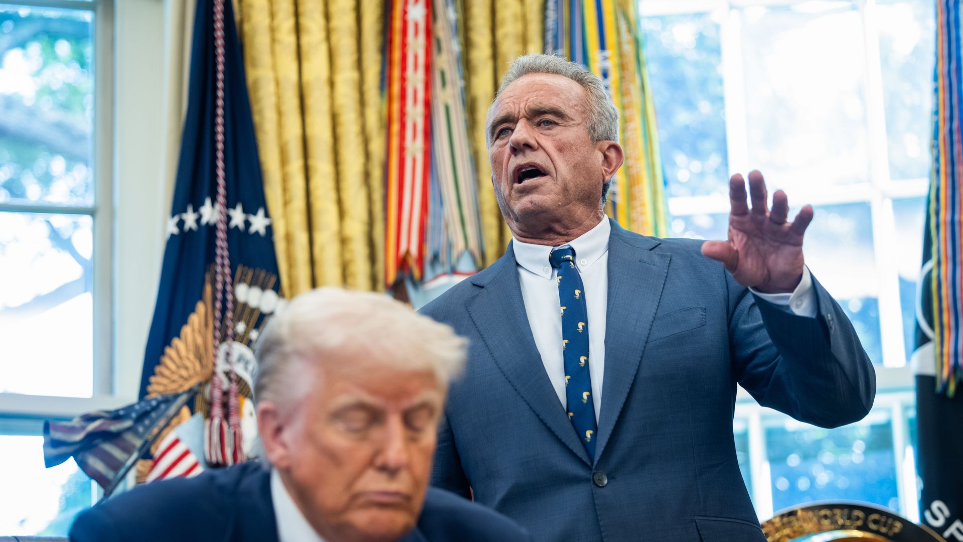 Robert F. Kennedy Jr. stands behind Donald Trump.