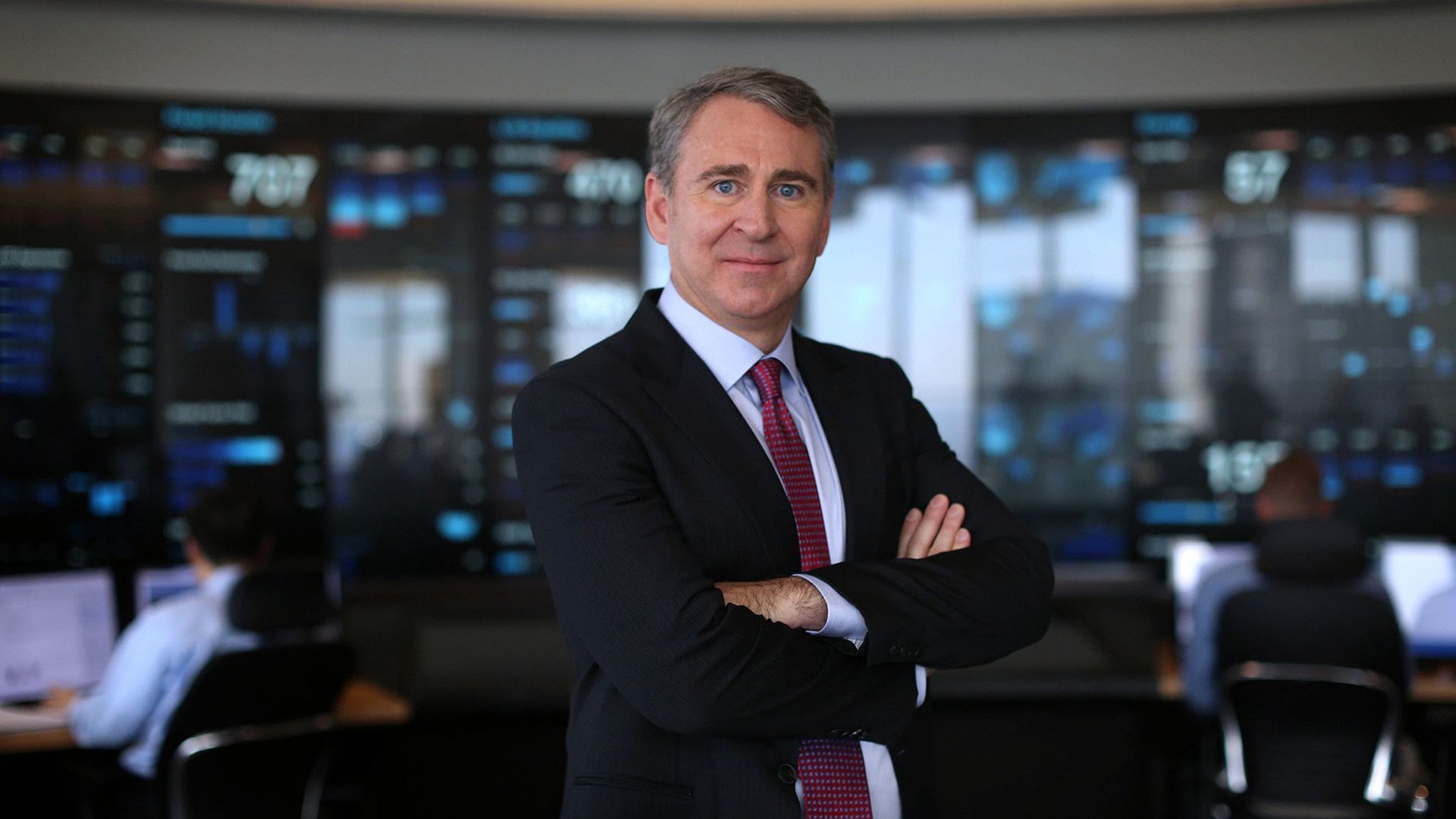 A photo of a man in a suit, folded arms.