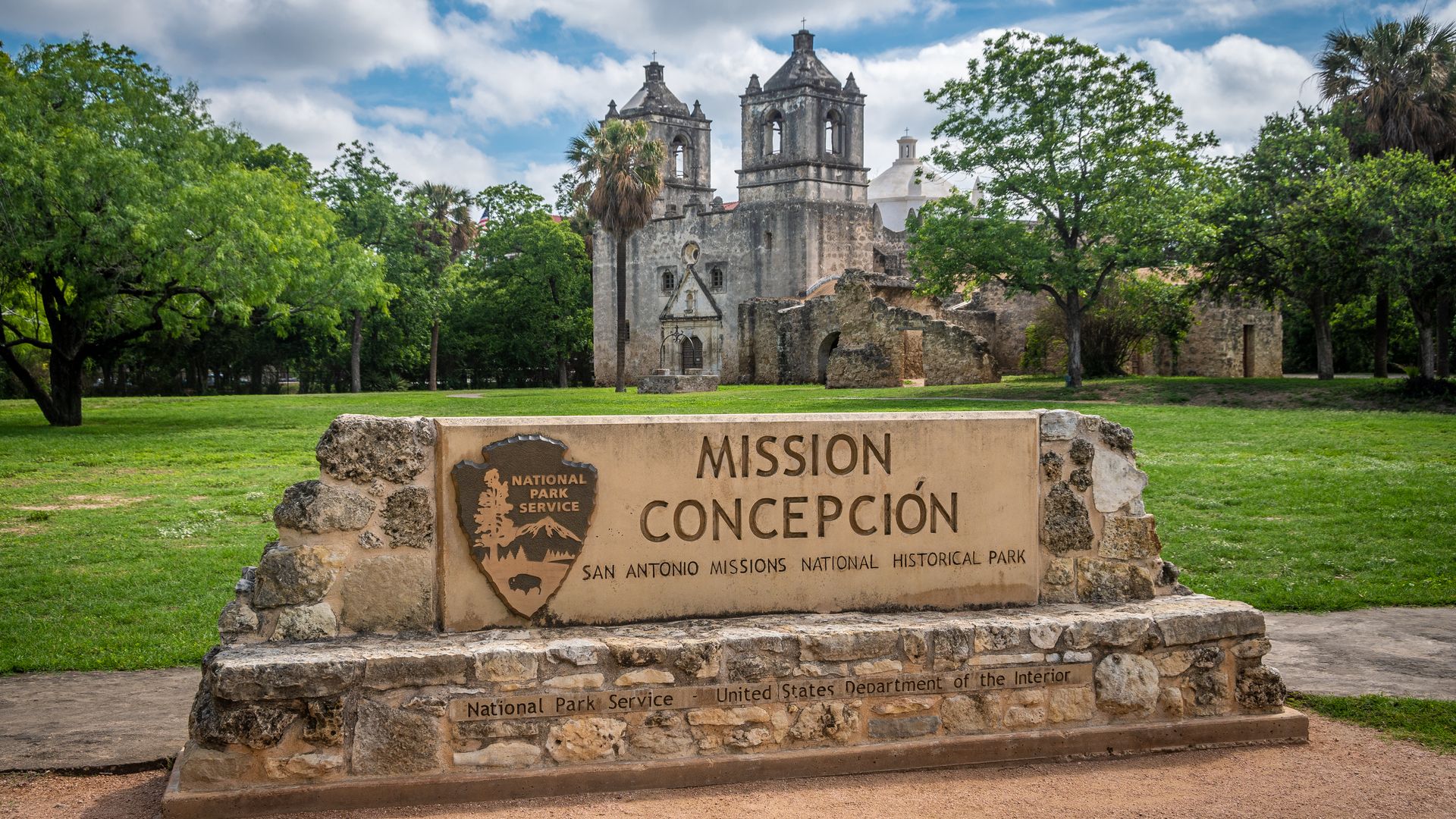 Mission Concepcion towering behind a National Park Service sign.