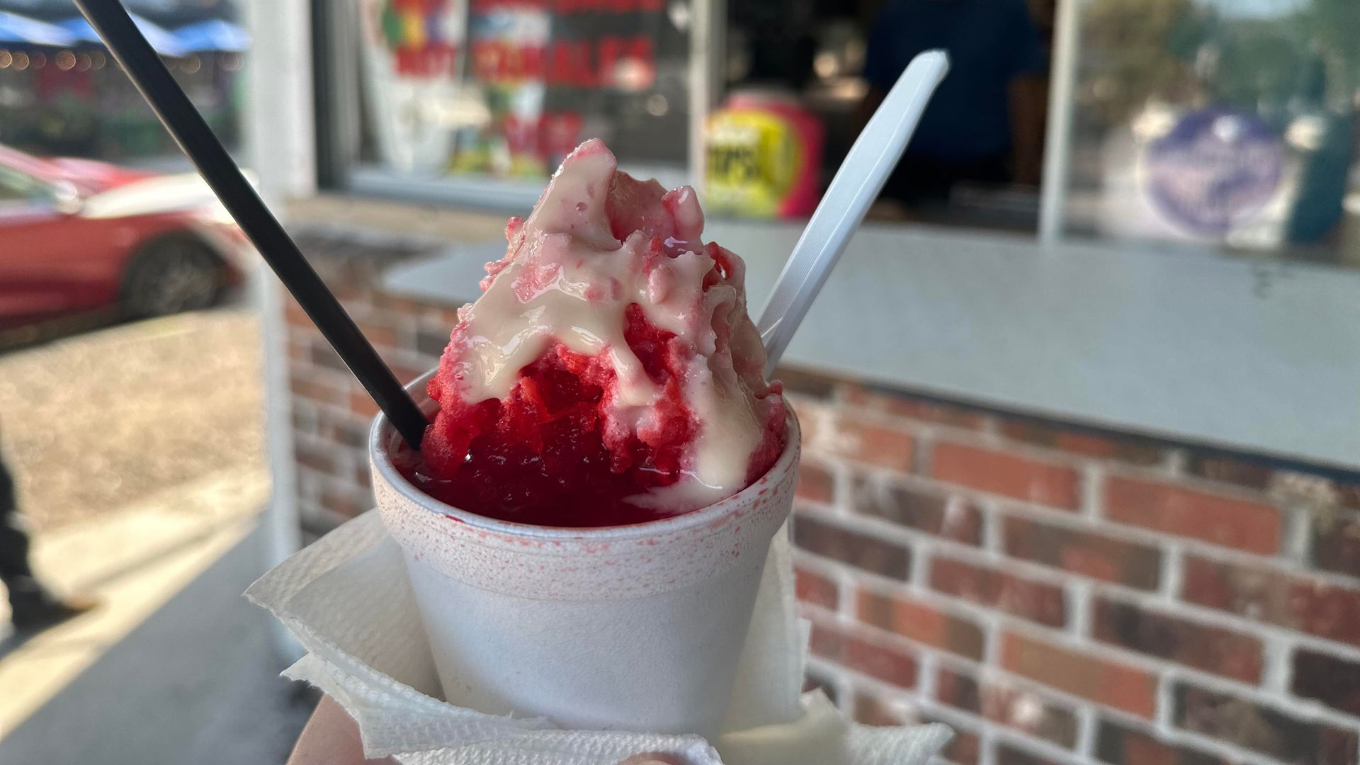 Photo shows a red strawberry snoball in a white styrofoam cup