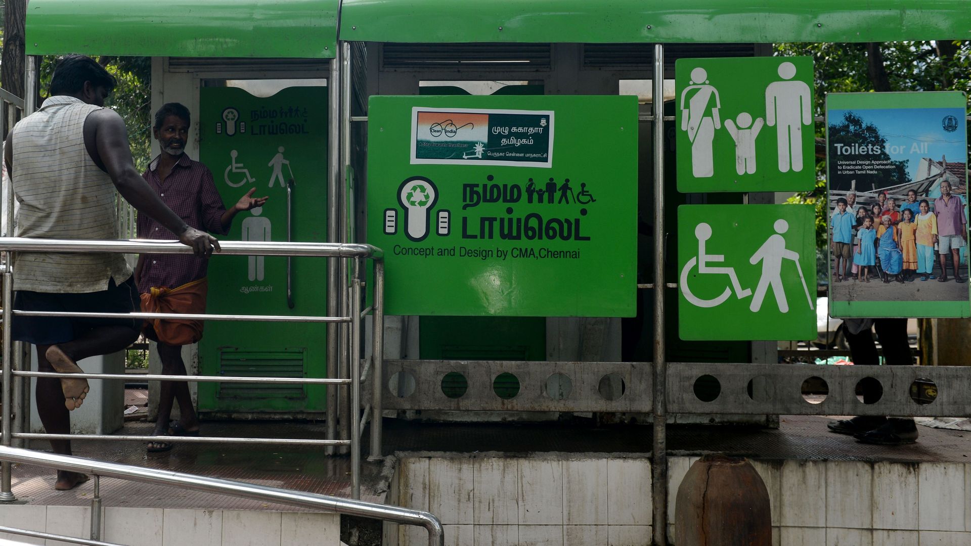 a public toilet on side of the street with two men standing in front