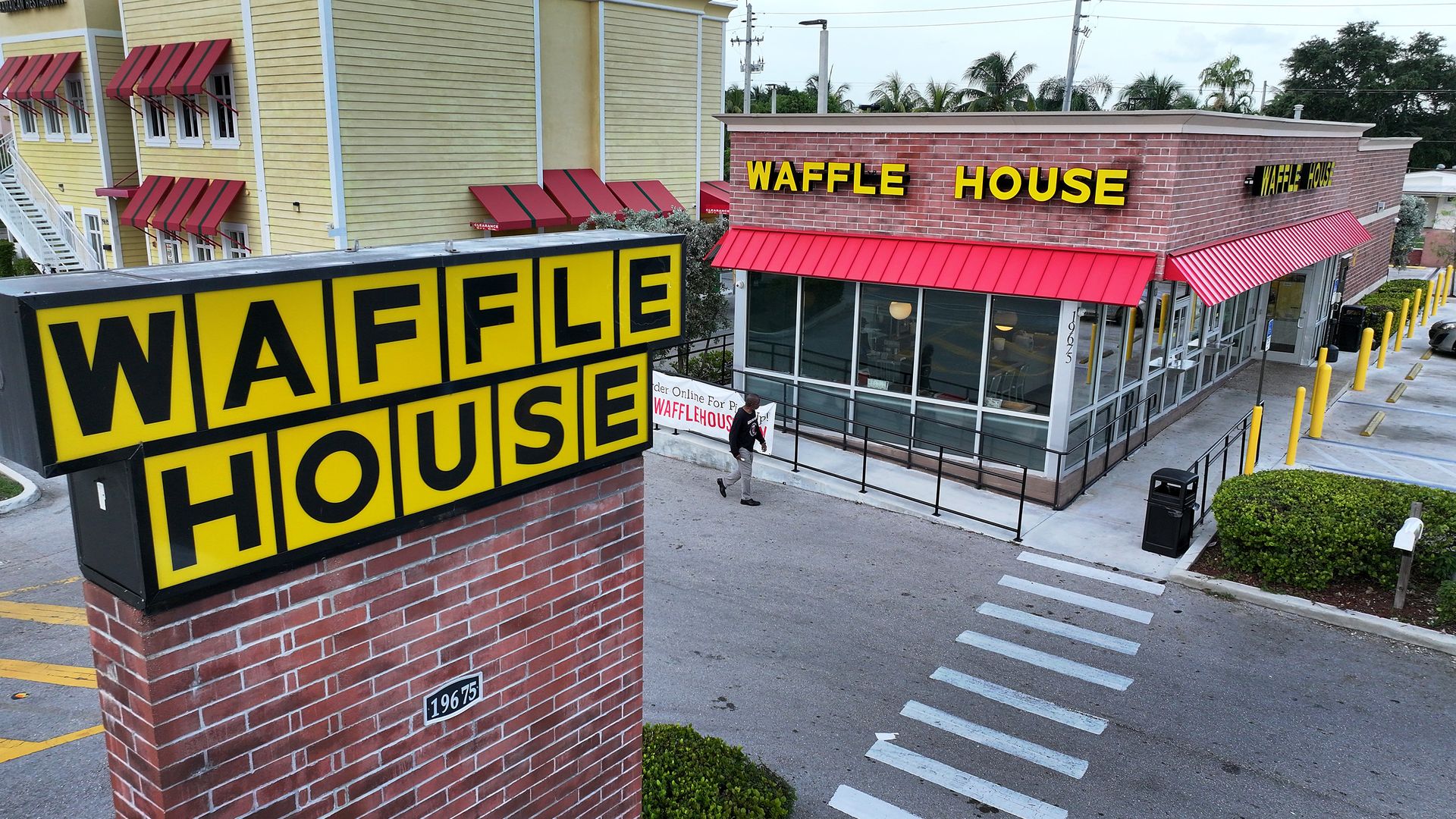 Exterior of a Waffle House restaurant with a Waffle House sign to the left of the restaurant